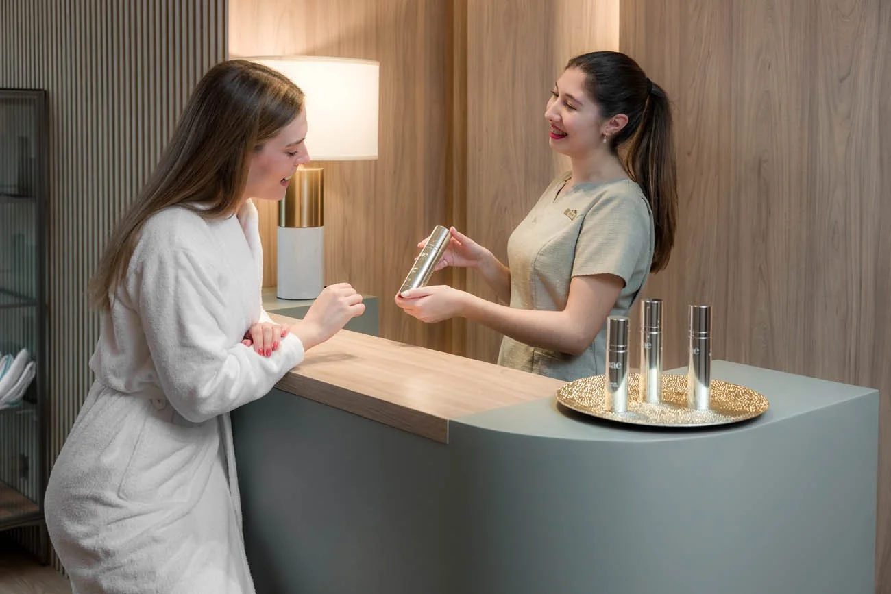 Recepcionista entregando produto de cuidados com a pele a uma hóspede em um hotel