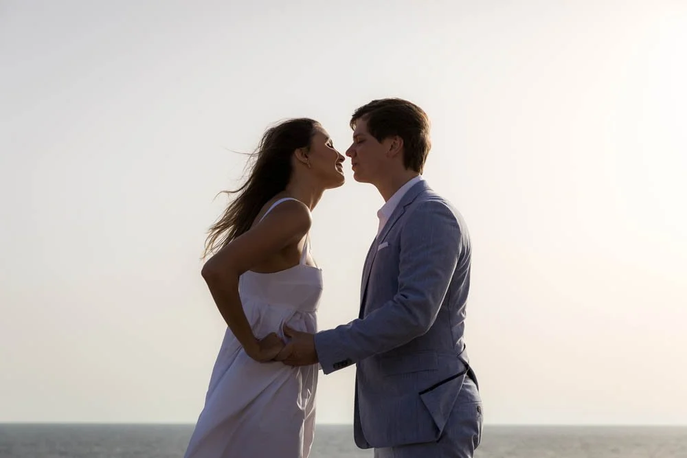 Casal romantico se beijando na praia ao pôr do sol