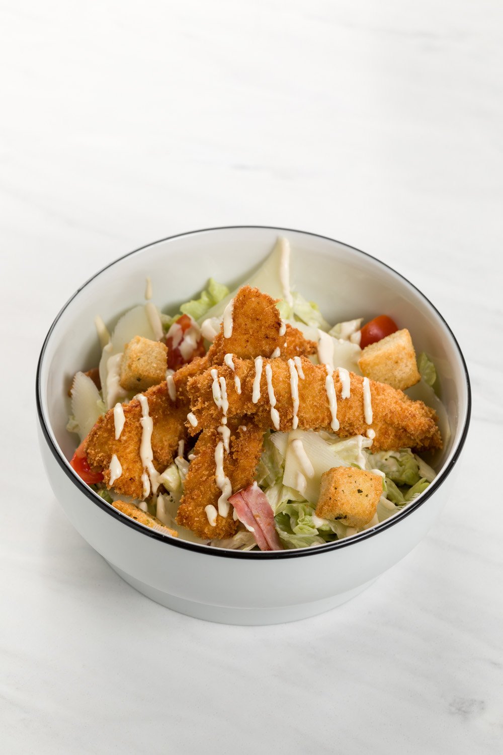 Salada de alface, tomate, cubos de pão e pedaços de frango empanado com molho branco