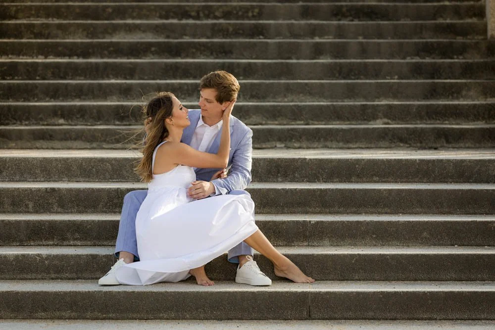 Casal sentando-se nas escadas, olhando um para o outro, em um momento romântico ao ar livre.