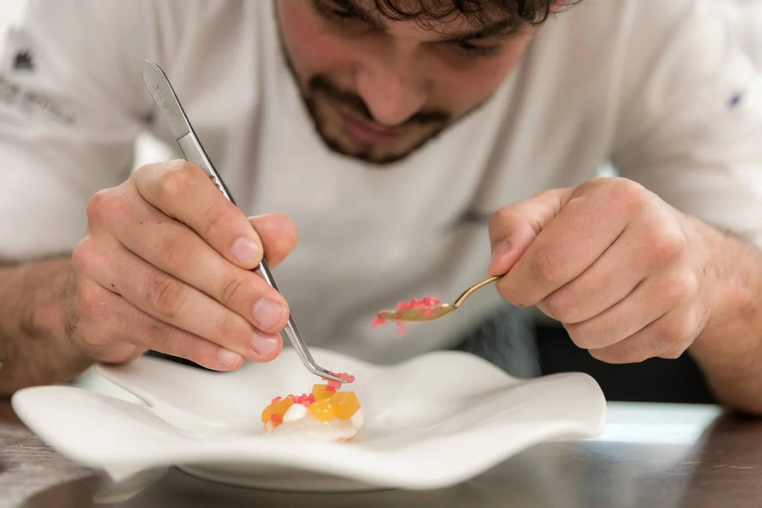 Chef decorando um prato com ferramentas de precisão em uma cozinha