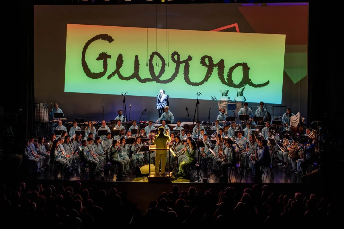 Orquestra em apresentação no palco com grande projeção de tela ao fundo que diz 'Guadua' em letras estilizadas.