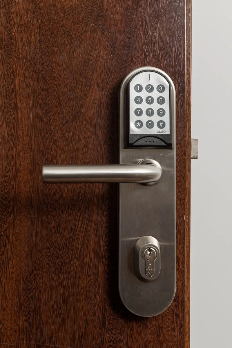 Fechadura eletrônica com teclado numérico instalada em uma porta de madeira.