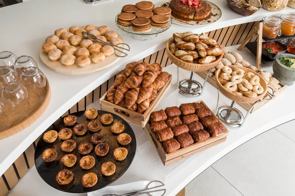 Buffet de café da manhã com pães, croissants, muffins, bolos e geleias