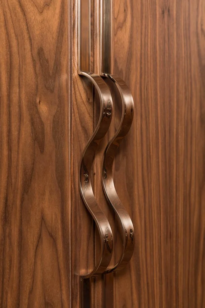 Fechadura de porta de madeira com alça de metal curva.