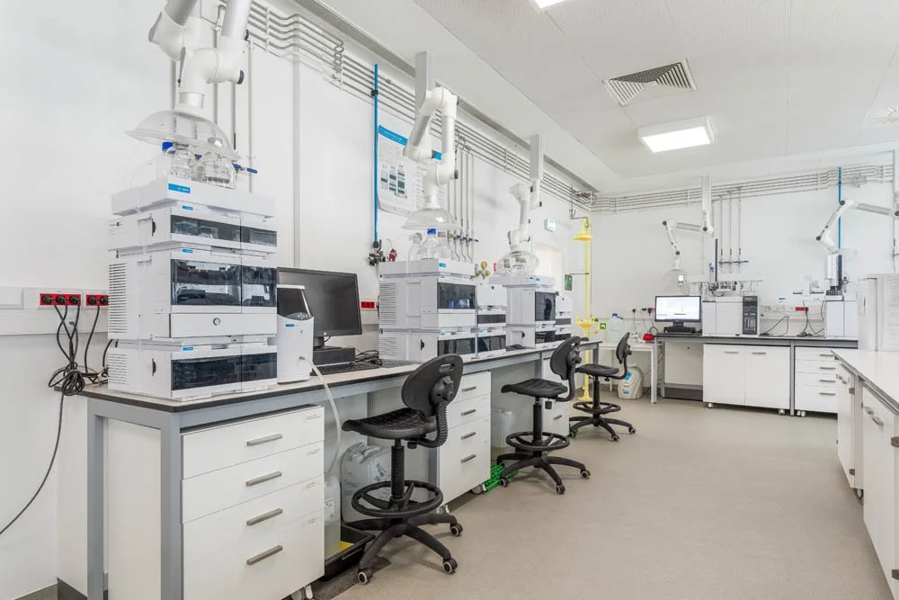 Laboratório com equipamentos de análise, computadores e cadeiras de escritório.