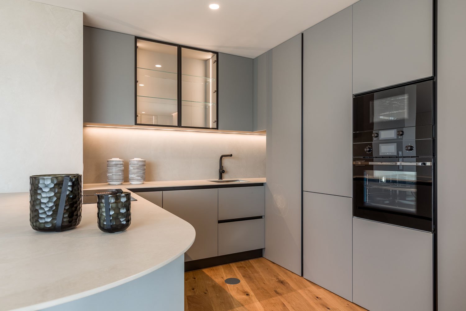 Cozinha moderna com armários cinza, bancada de mármore, por-do-sol, decorada com vasos e utensílios.