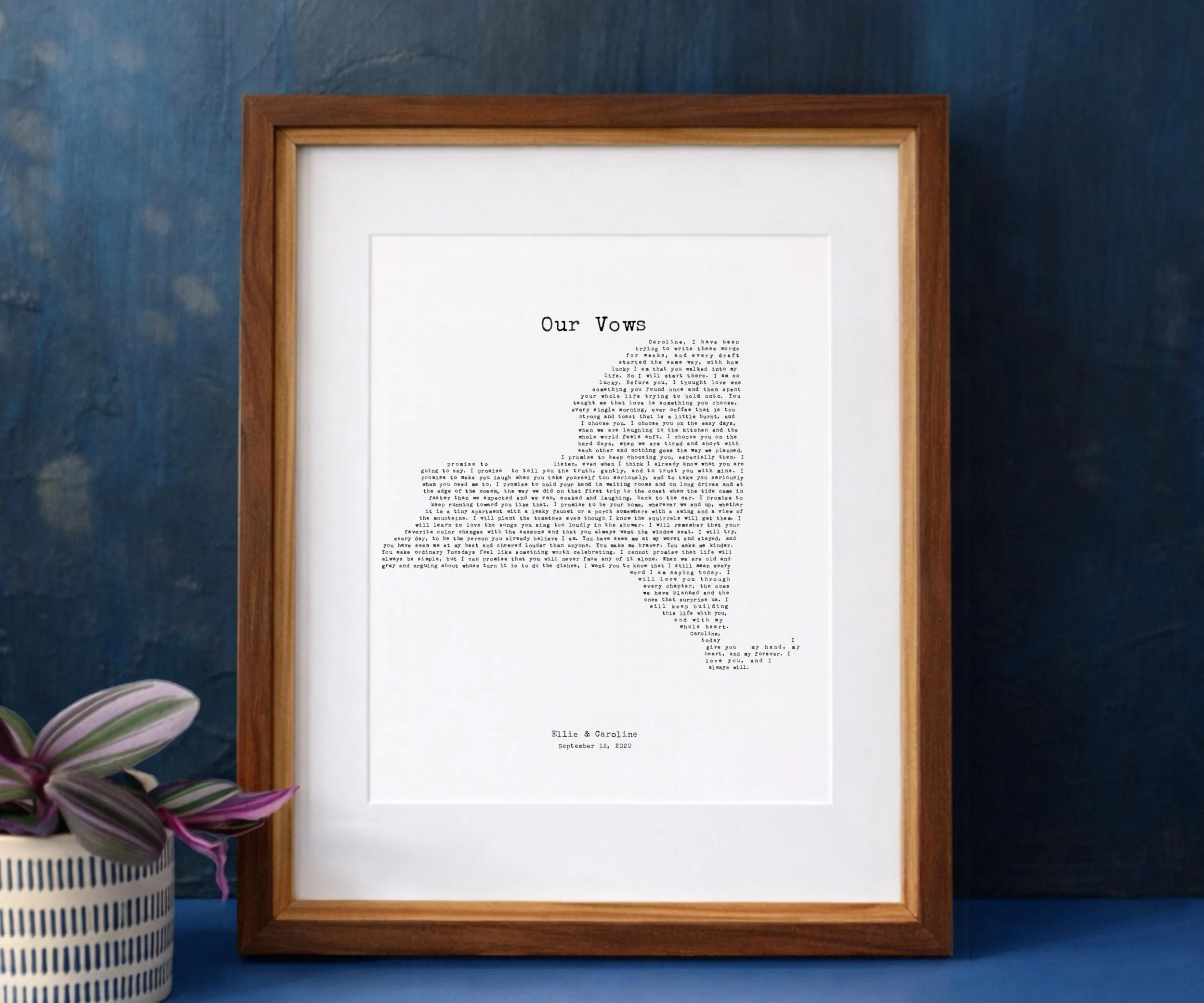 New York wedding vows print typed in a typewriter font, framed in walnut against a navy wall