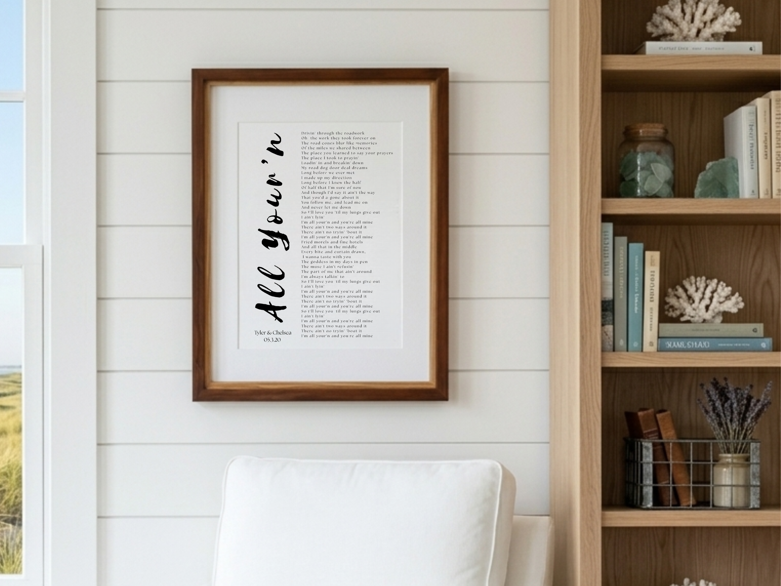Framed custom wedding song lyrics print in a walnut frame on a white shiplap wall above a sofa