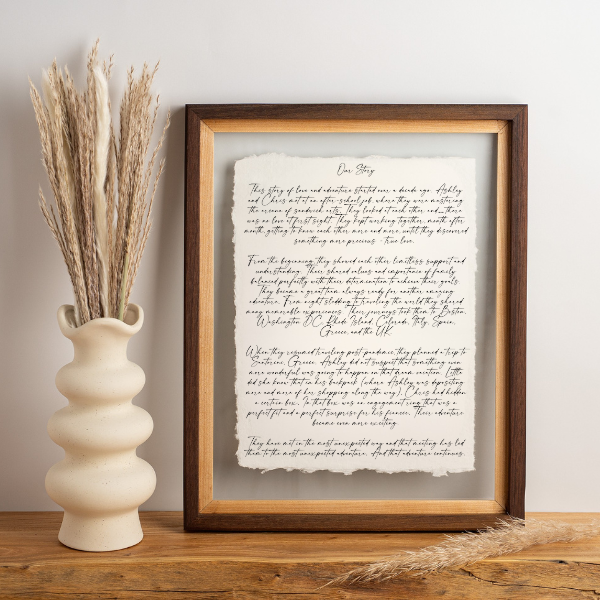 Framed handwritten couples story on cotton rag paper, styled with neutral home decor — a perfect personalized wedding or anniversary gift.