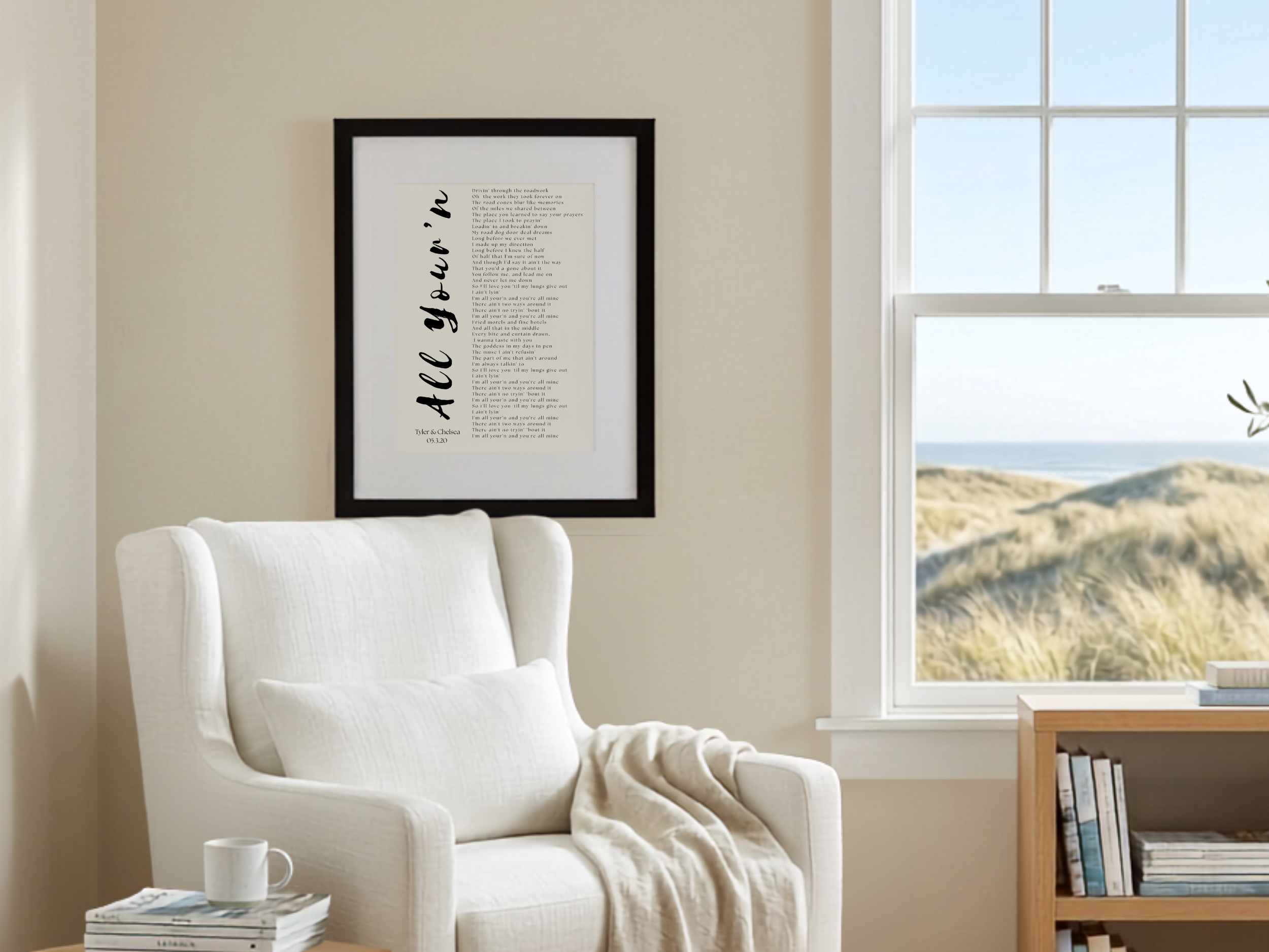 Personalized All Your'n song lyrics print in a black frame hanging above a white armchair in a coastal reading nook