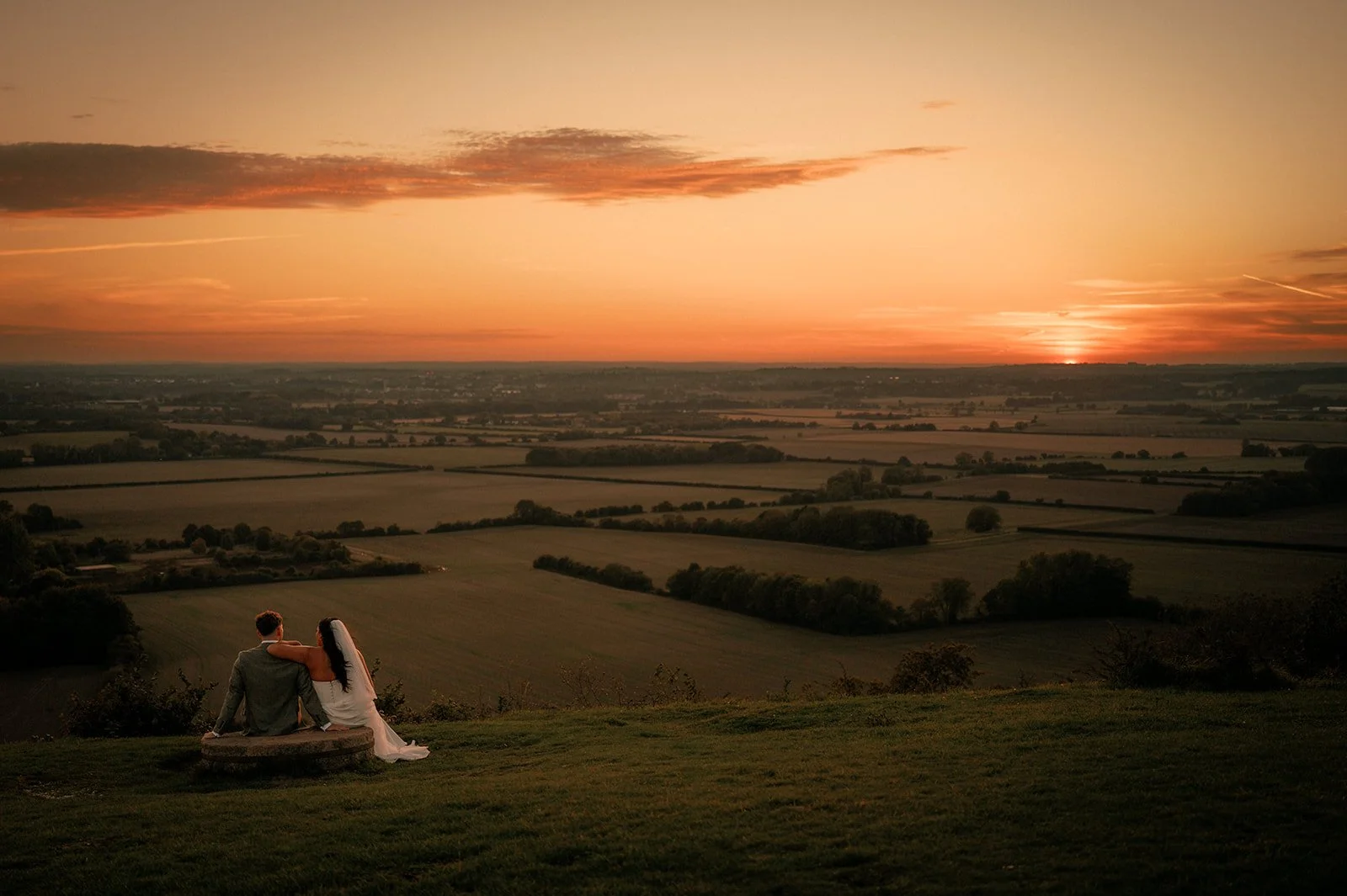 Wedding photographer capturing ceremony a moment of a brdie and groom watching the sunset on their wedding day with unobtrusive presence