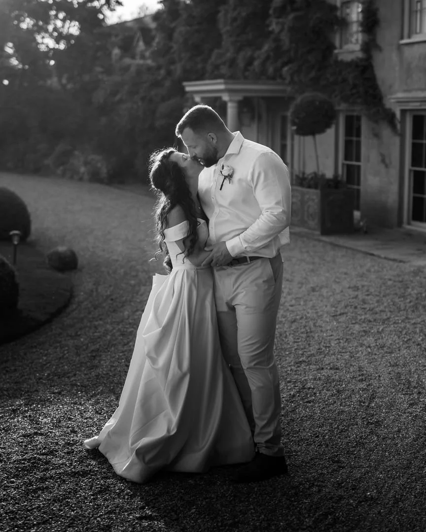 Newly wed couple share a kiss in the warmth of a sunset at The Old Rectory in Kent.