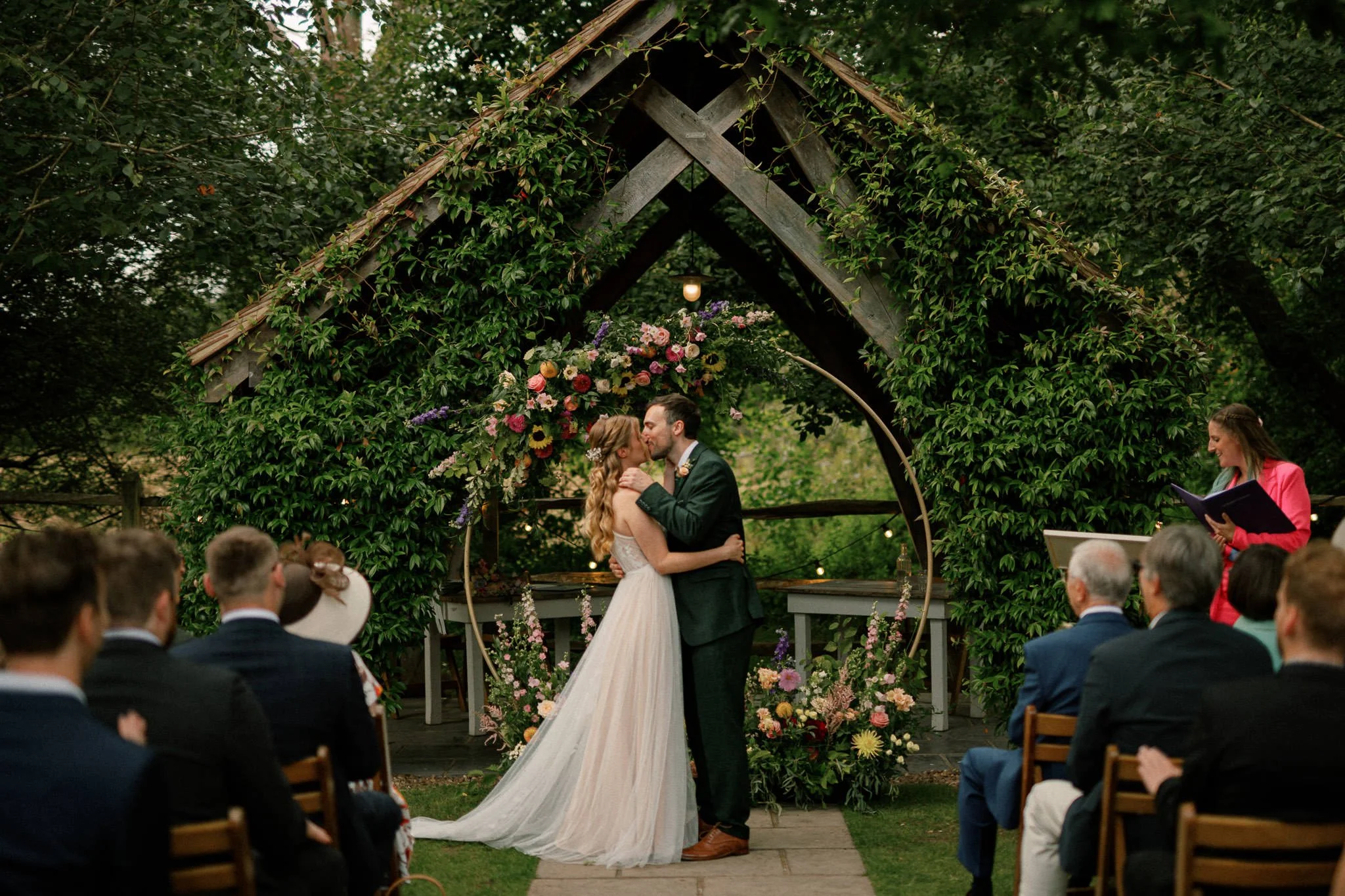 Husband and wife exchange their first kiss in the outside ceremony space on their wedding day at Millbridge Court, Surrey.