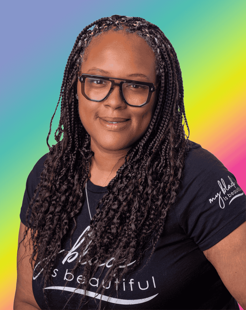 Headshot of GYO-IL Graduate Kimmika Johnson on a rainbow gradient background. Kimmika has dark skin, long micro braids, and wears funky black glasses.