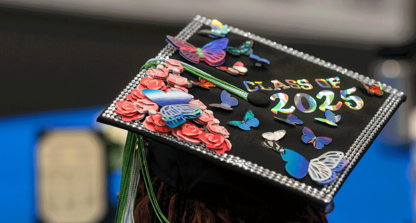 Detail shot of a Class of 2025 graduation mortar board decorated with reflective butterflies and flowers.