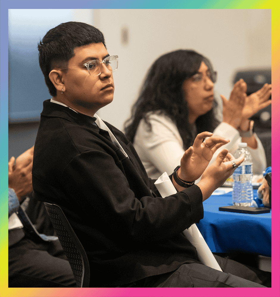 GYO-IL Graduate Juan Najera clapping at the graduation ceremony. He is Latino with short hair and clear glasses.