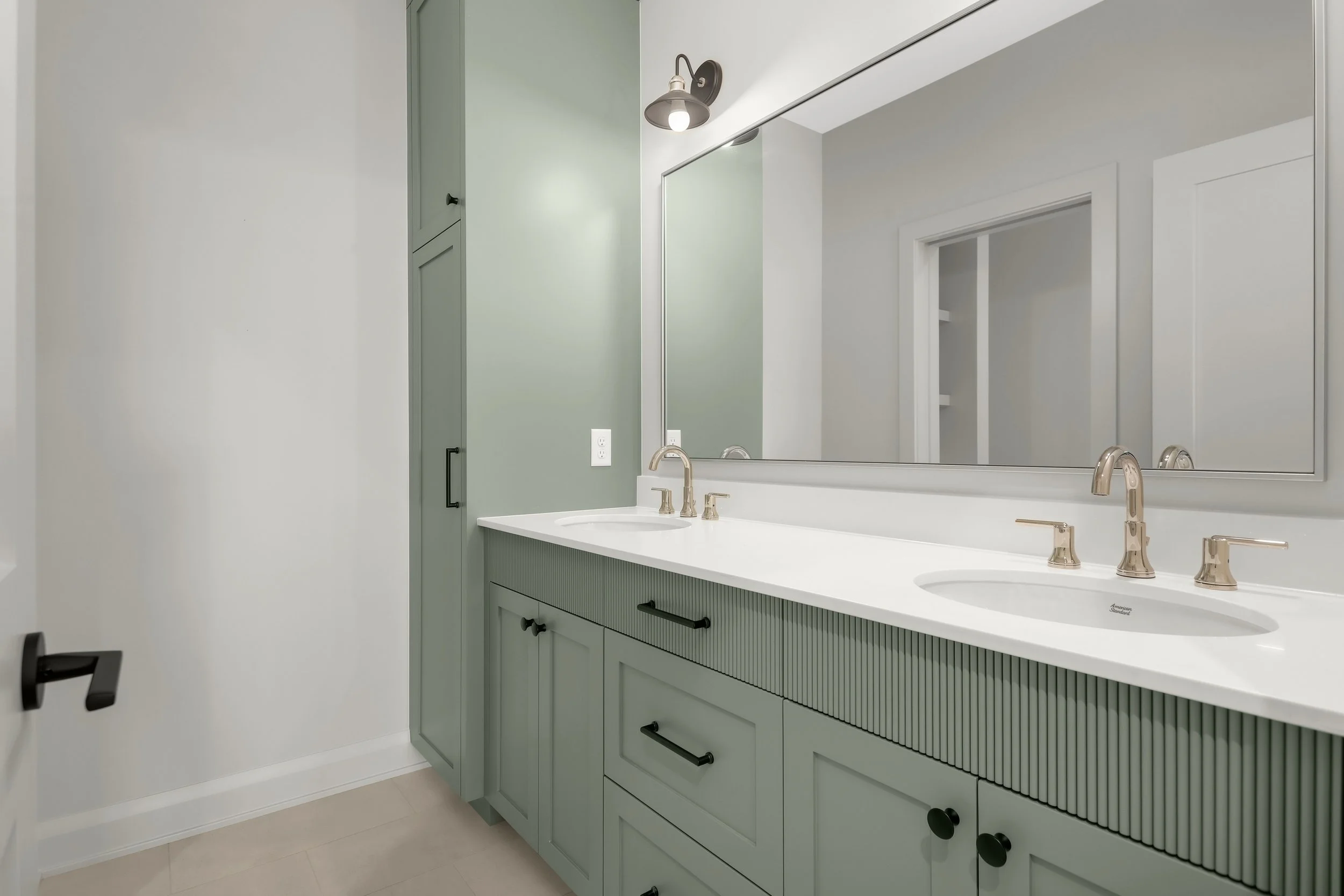 Modern bathroom with sage green double vanity, white countertop, dual sinks, large mirror, and brushed nickel faucets