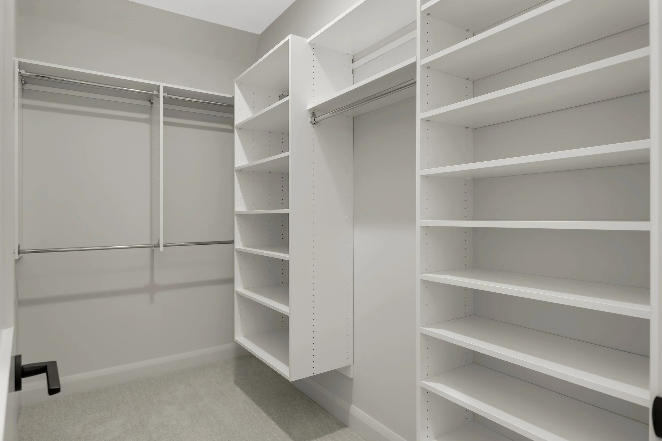 Spacious white walk-in closet with built-in shelving, adjustable shelves, and double hanging rods