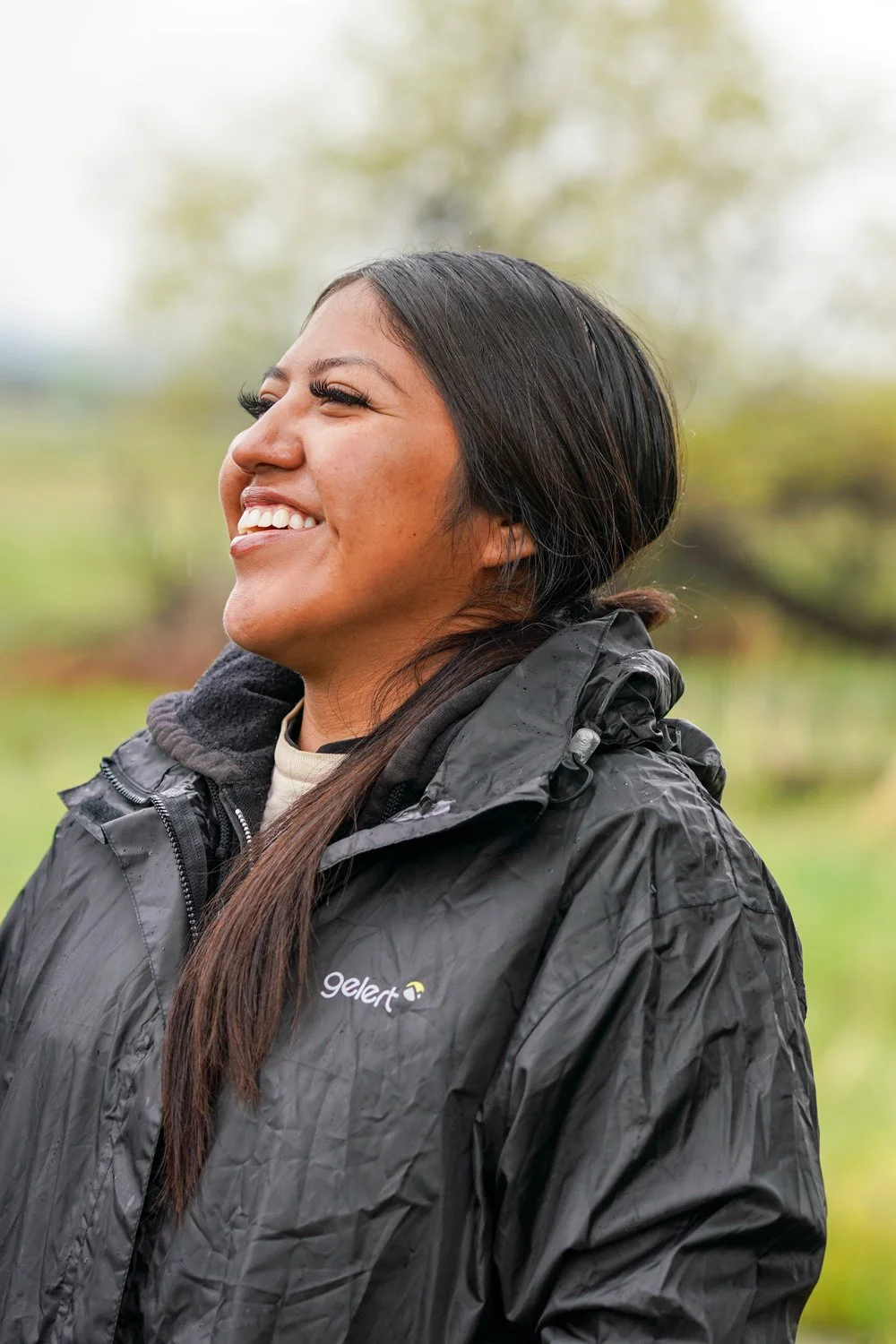 Youth worker with black rain coat laughing. This photo was taken on a work day for the Traditional Harvest Prject in Southwest Colorado.