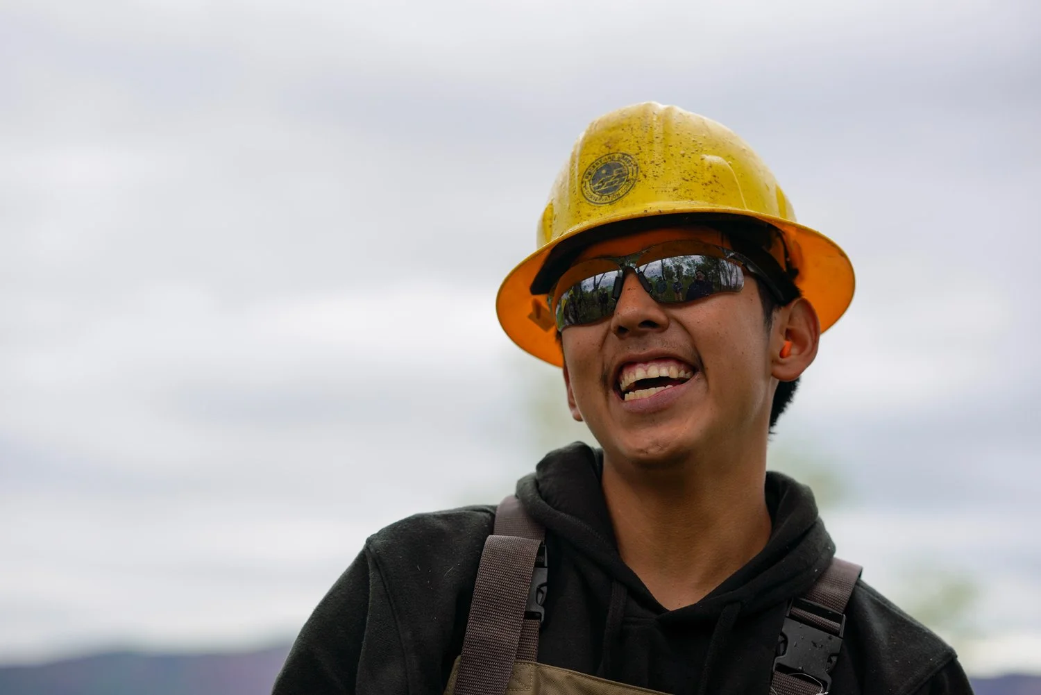 Youth worker in yeallow construction hat  working on the traditional Harvest Project in Southwest Colorado