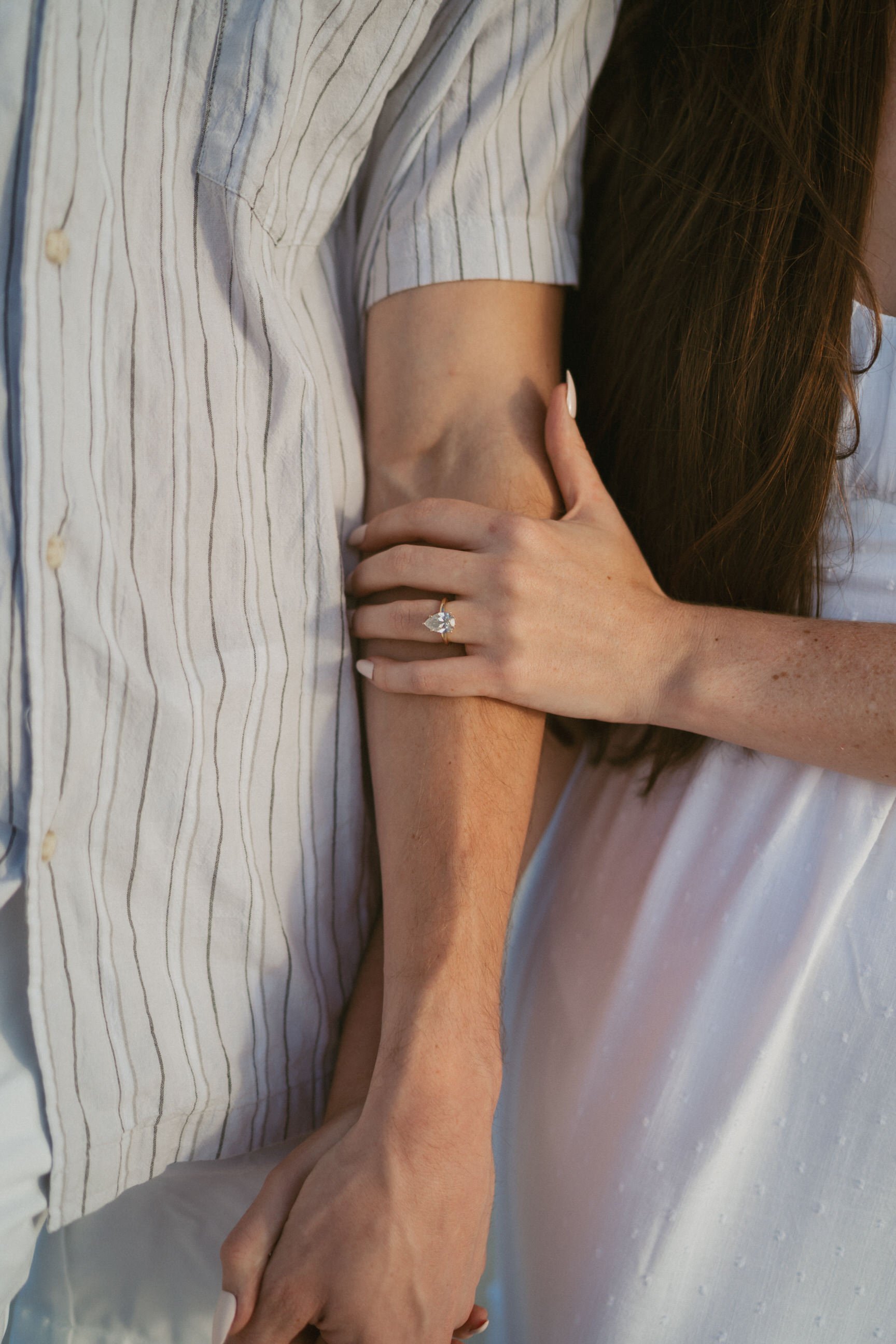 close up photo of unique engagement ring and couple holding each other