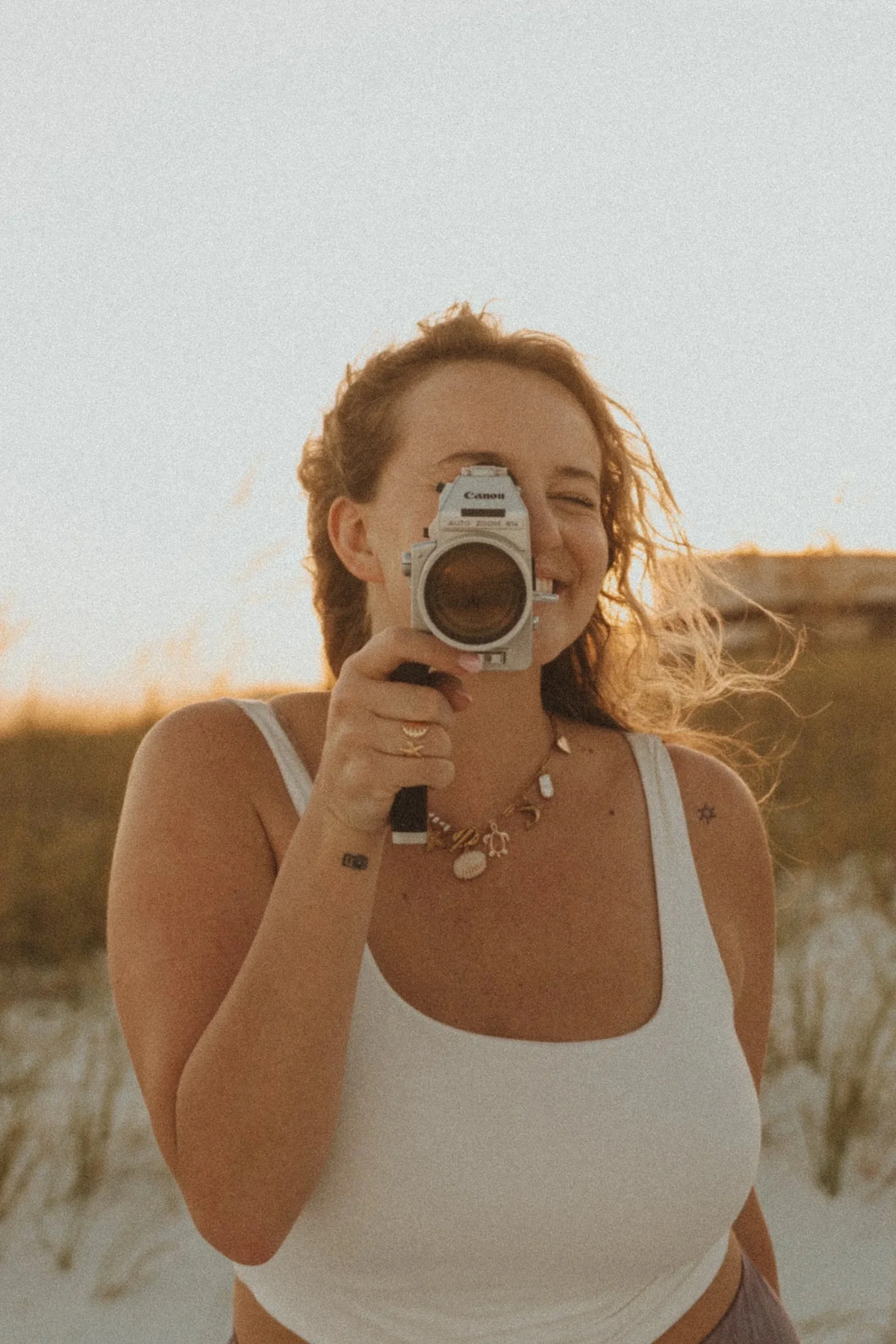 photographer holding a super 8 camera on the beach