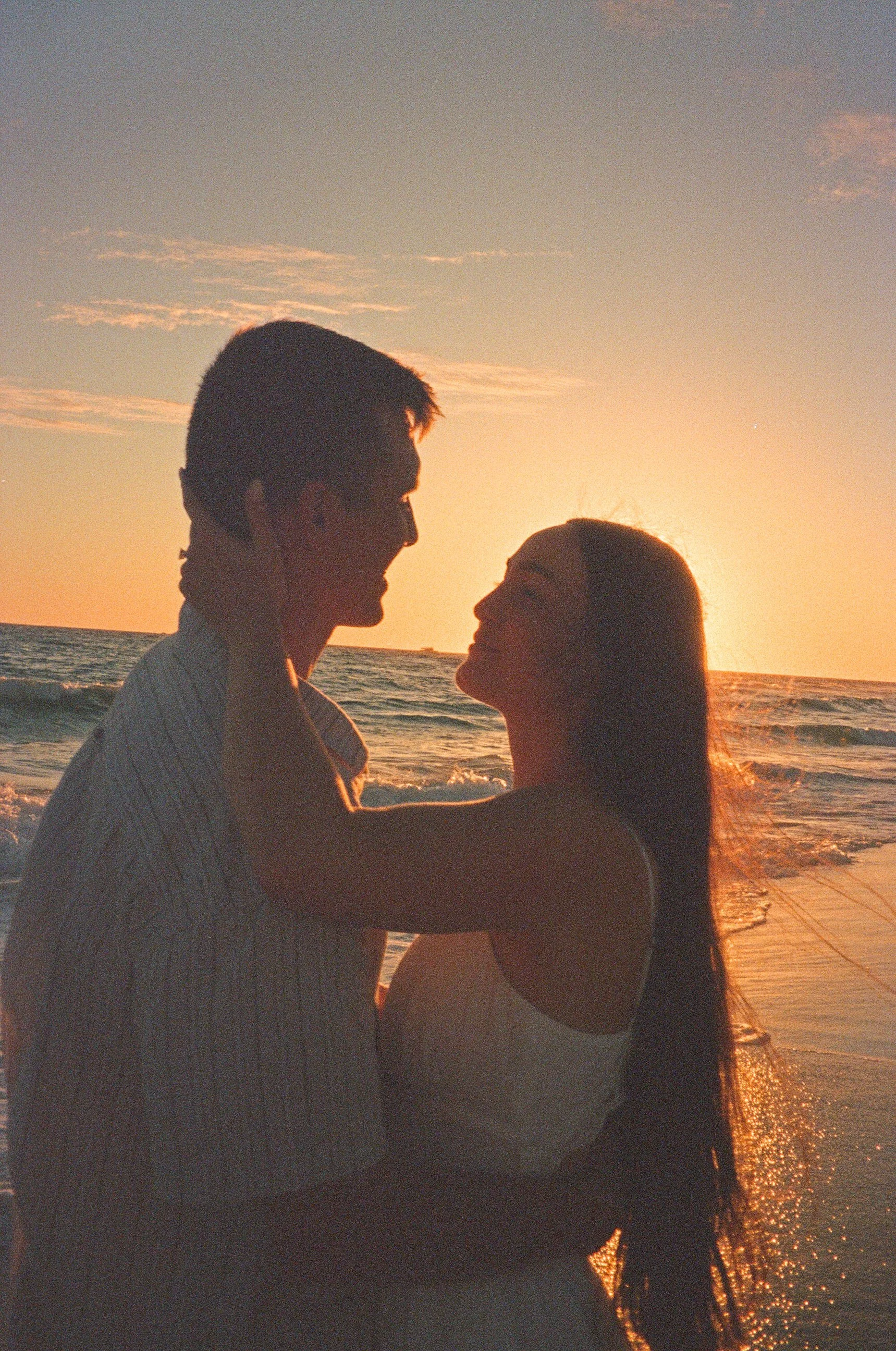 A silhouette of a couple embracing on the beach during sunset.