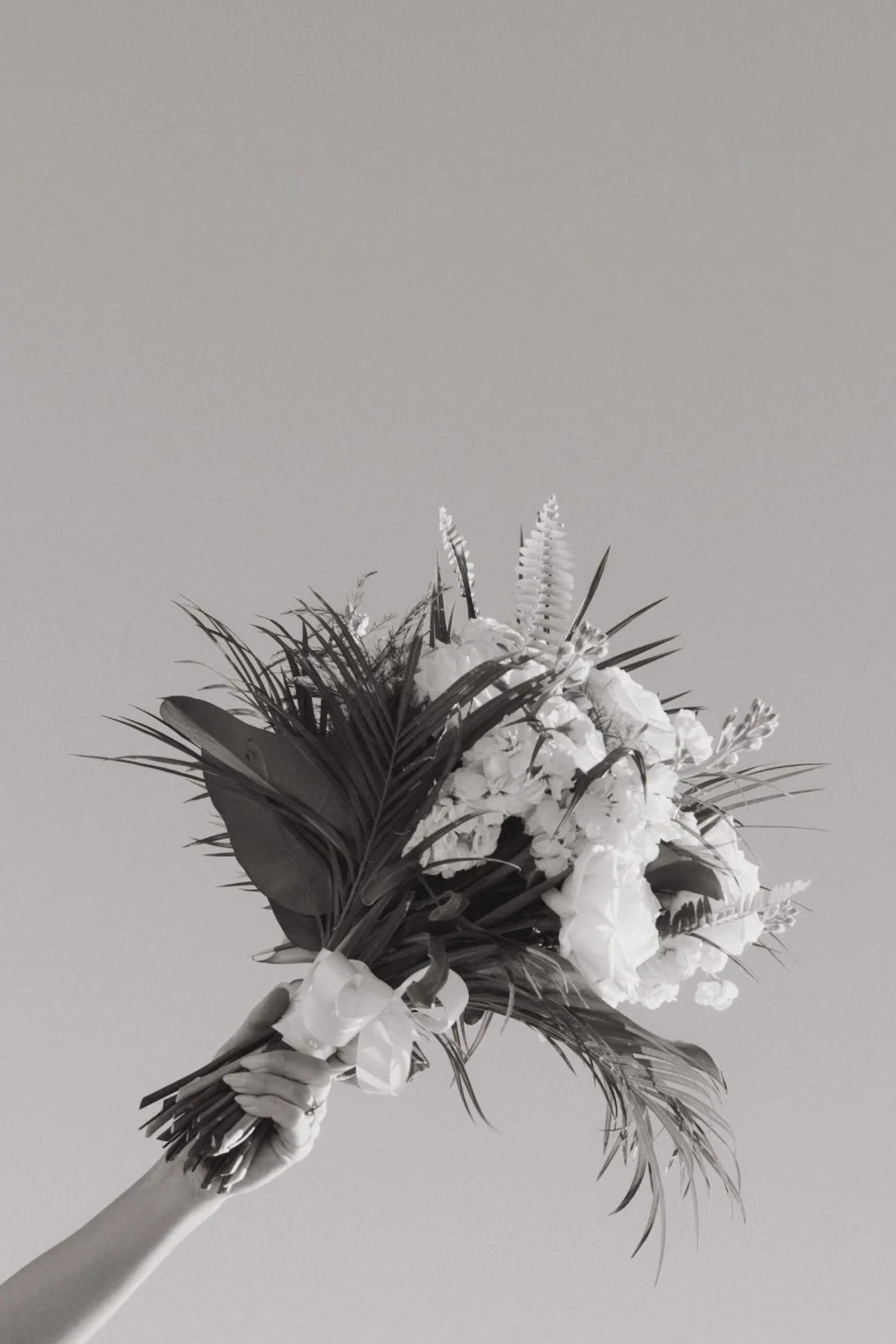 Person holding a bouquet of flowers against a plain background.
