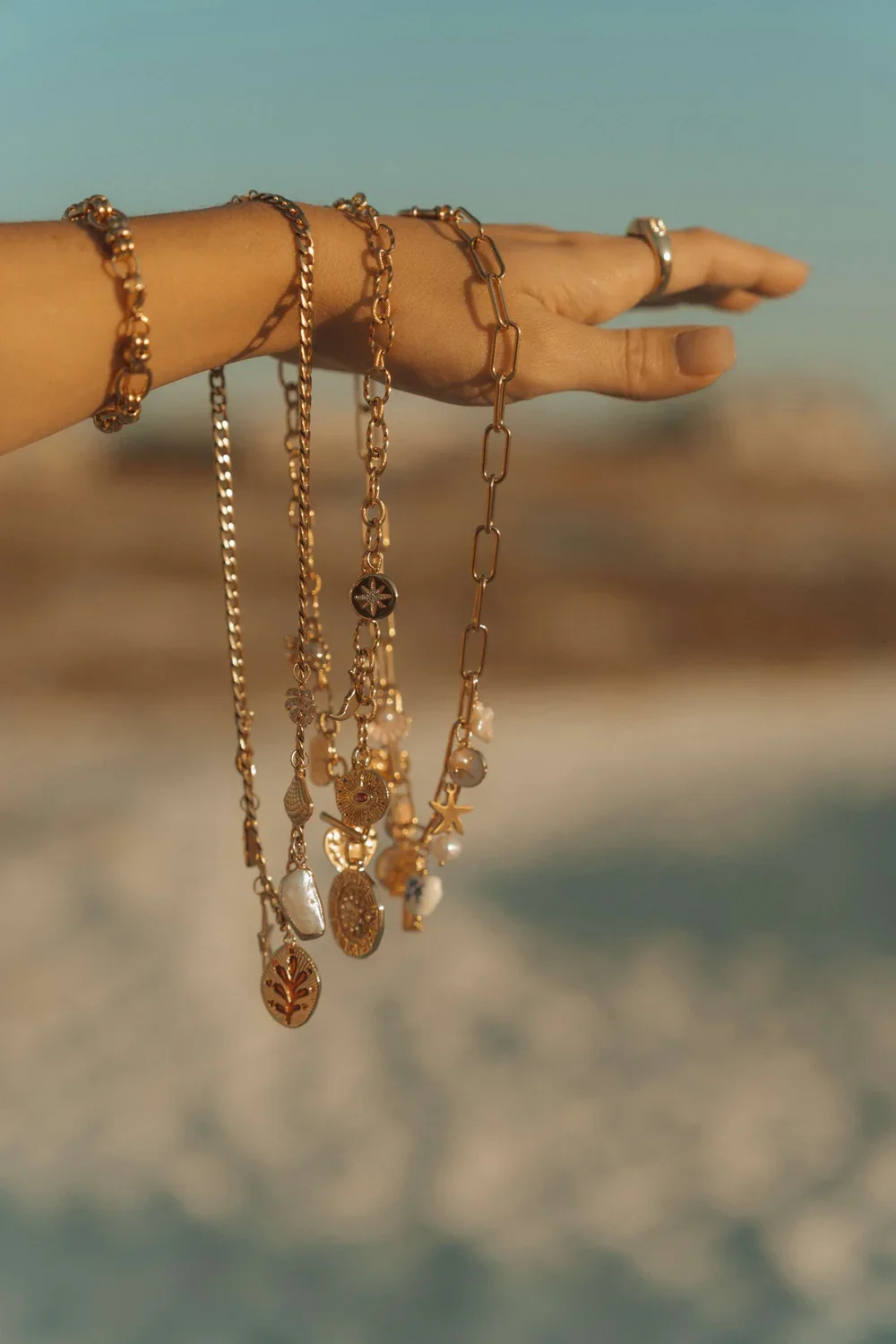 arm holding a collection of beach inspired jewelry