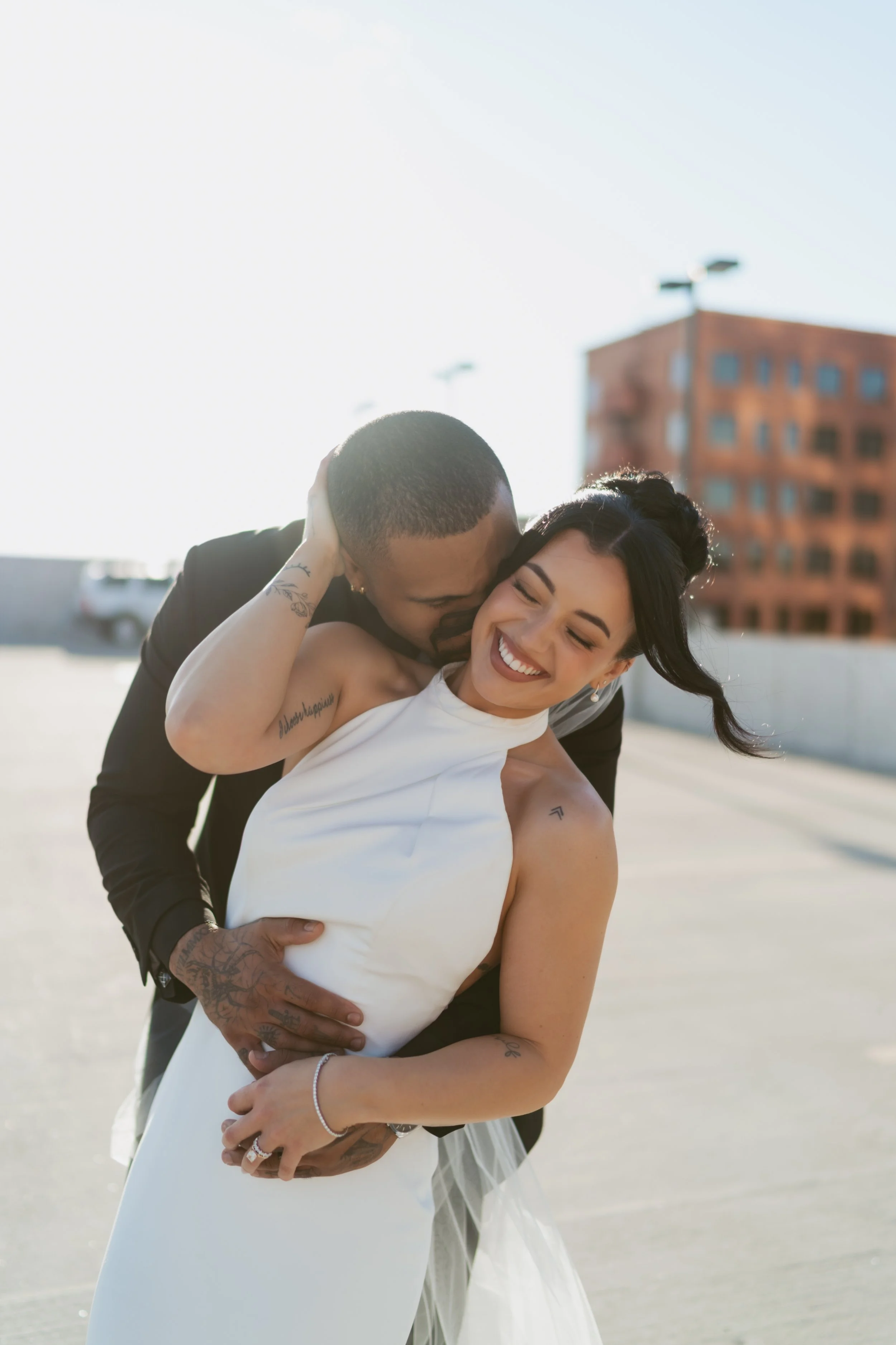  Bride and groom laughing together on their wedding day during their romantic wedding portraits on a rooftop of a parking garage  