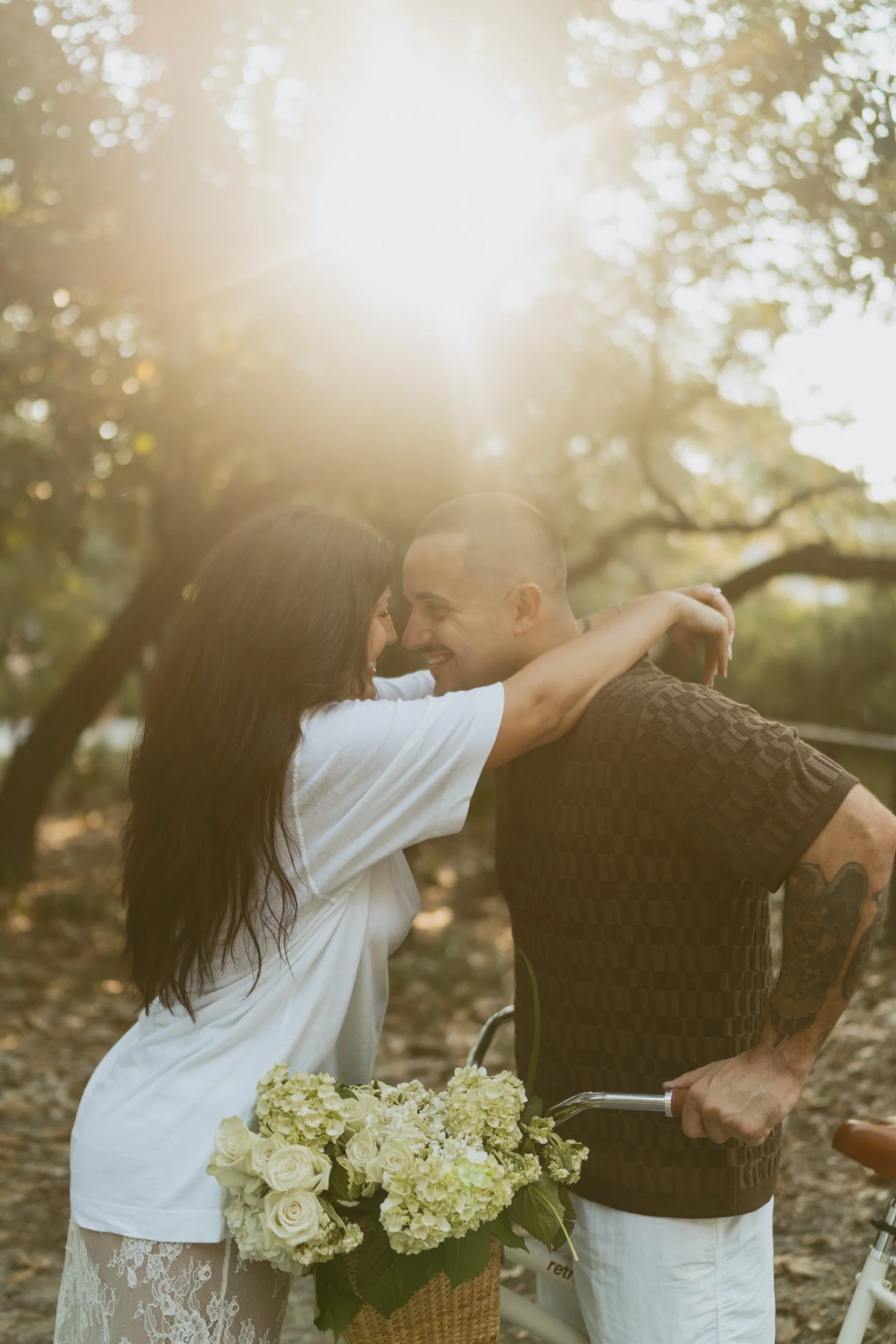 Couple is hugging closely while on bike with florals in the basket