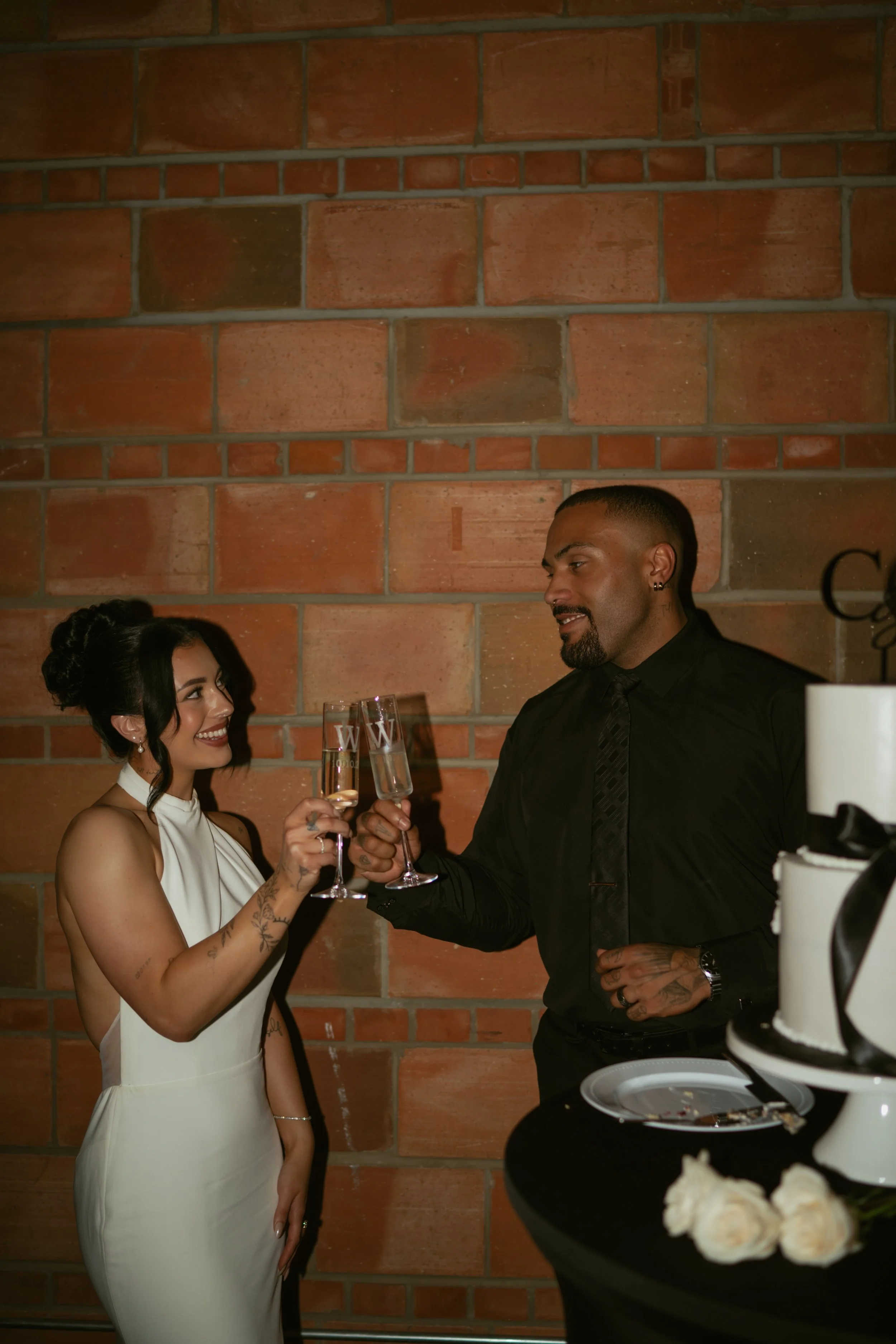  bride and groom cheersing with custom champagne glasses by their wedding cake after cutting it  