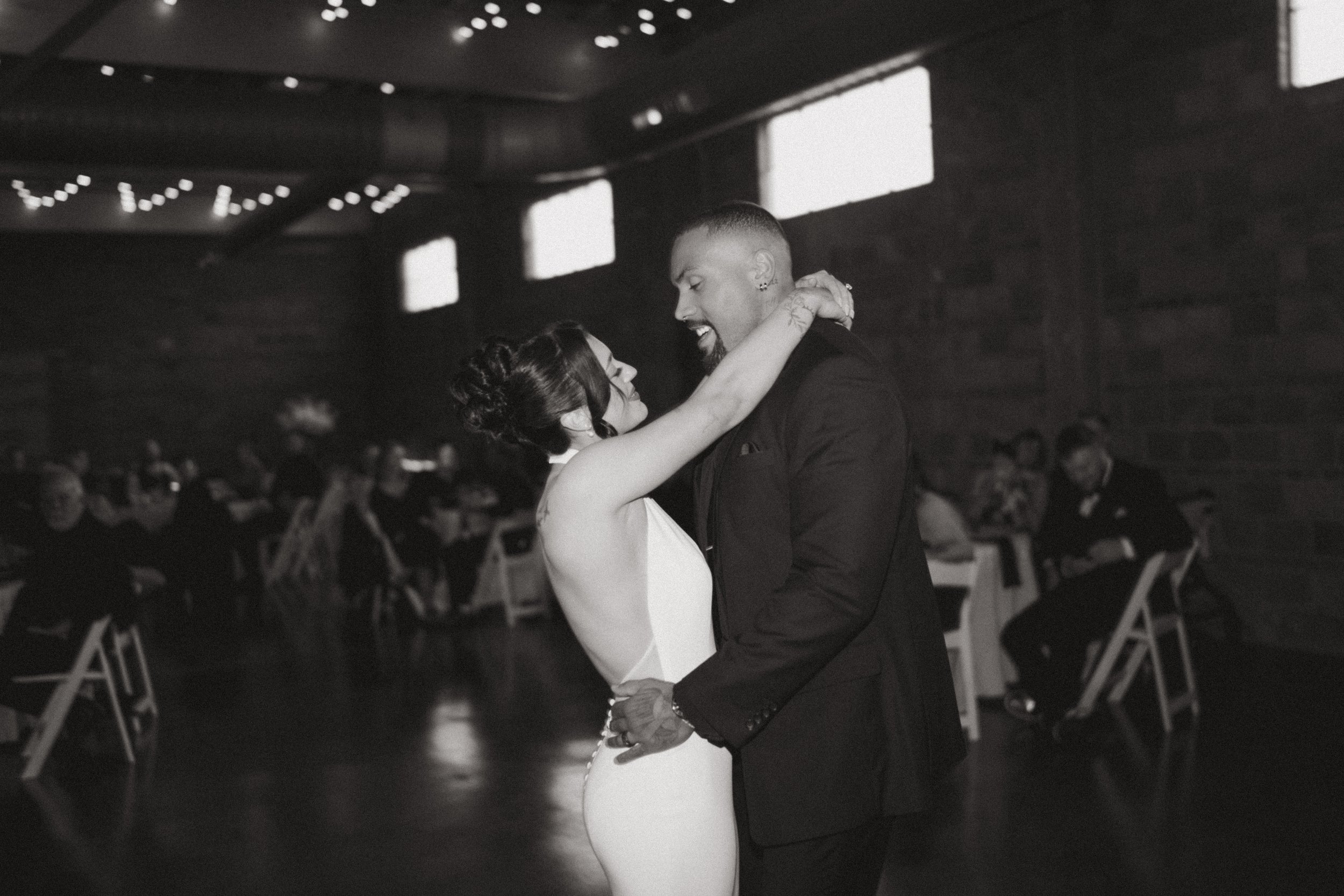  black and white photo of bride and groom smiling with each other during their first dance  