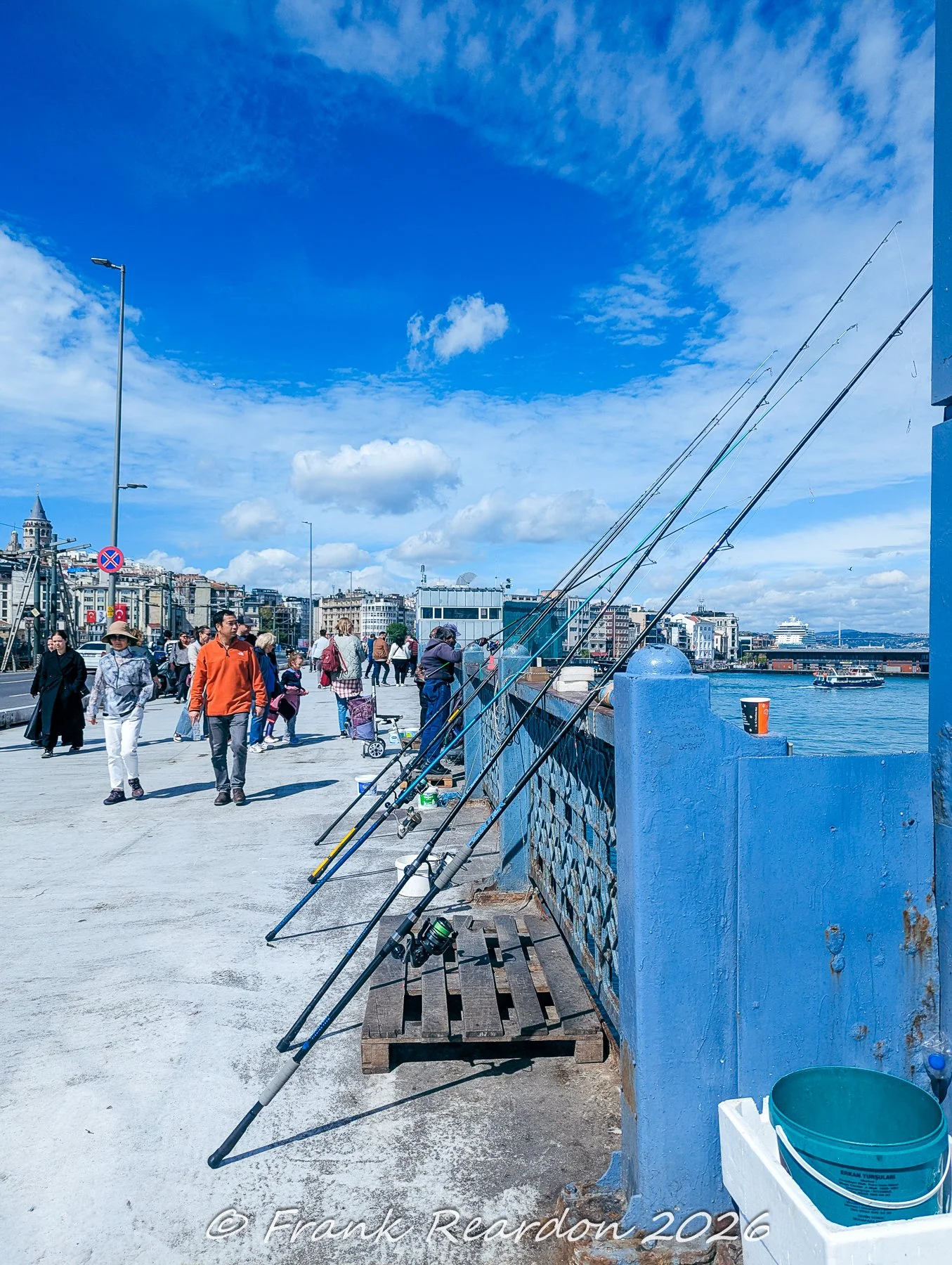 A row of fishing poles set up along the edge of the Galata Bridge, a popular gathering spot for local anglers looking out over the water.