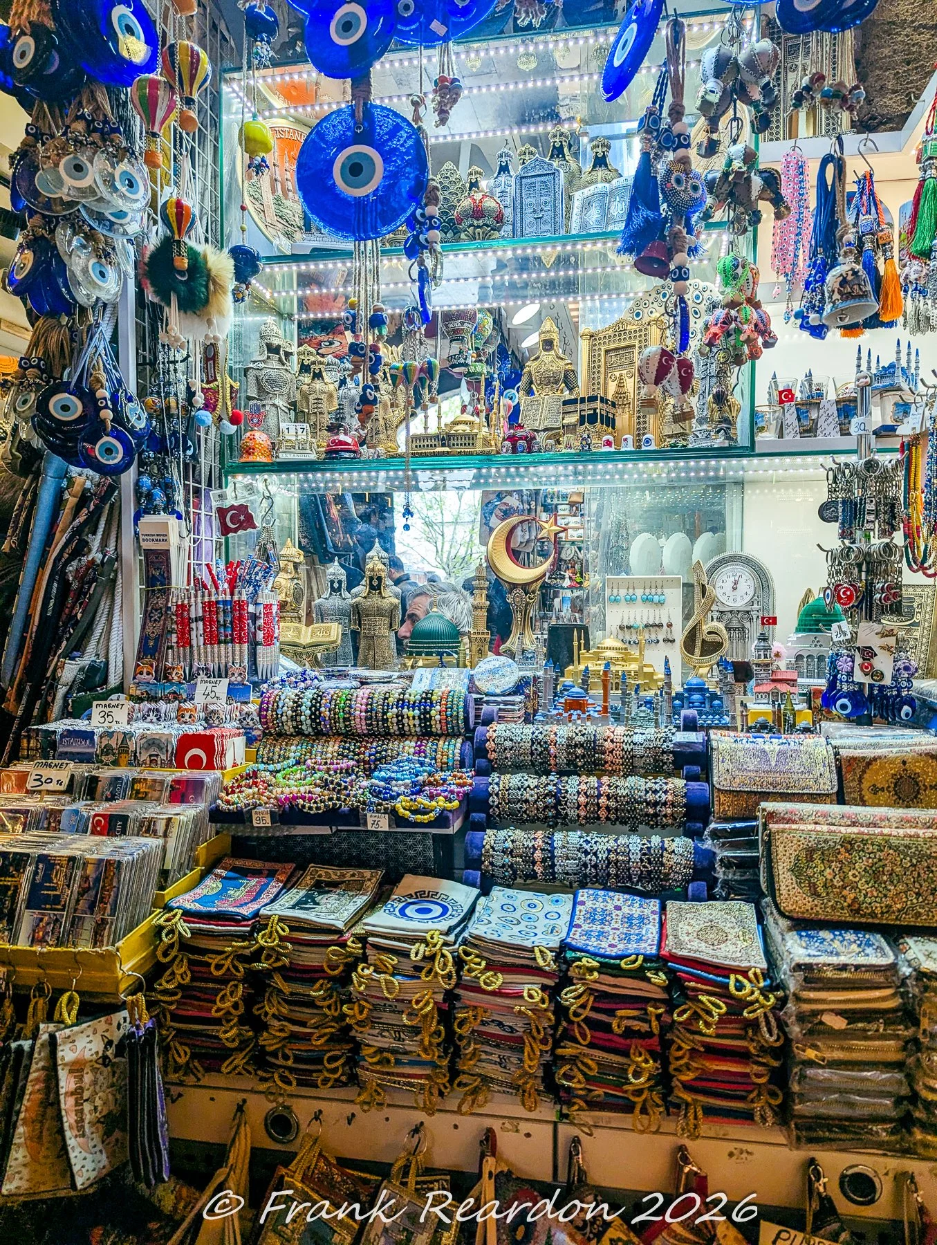A shop window display featuring hanging blue evil eye glass talismans, beaded bracelets, and traditional souvenirs in Istanbul.