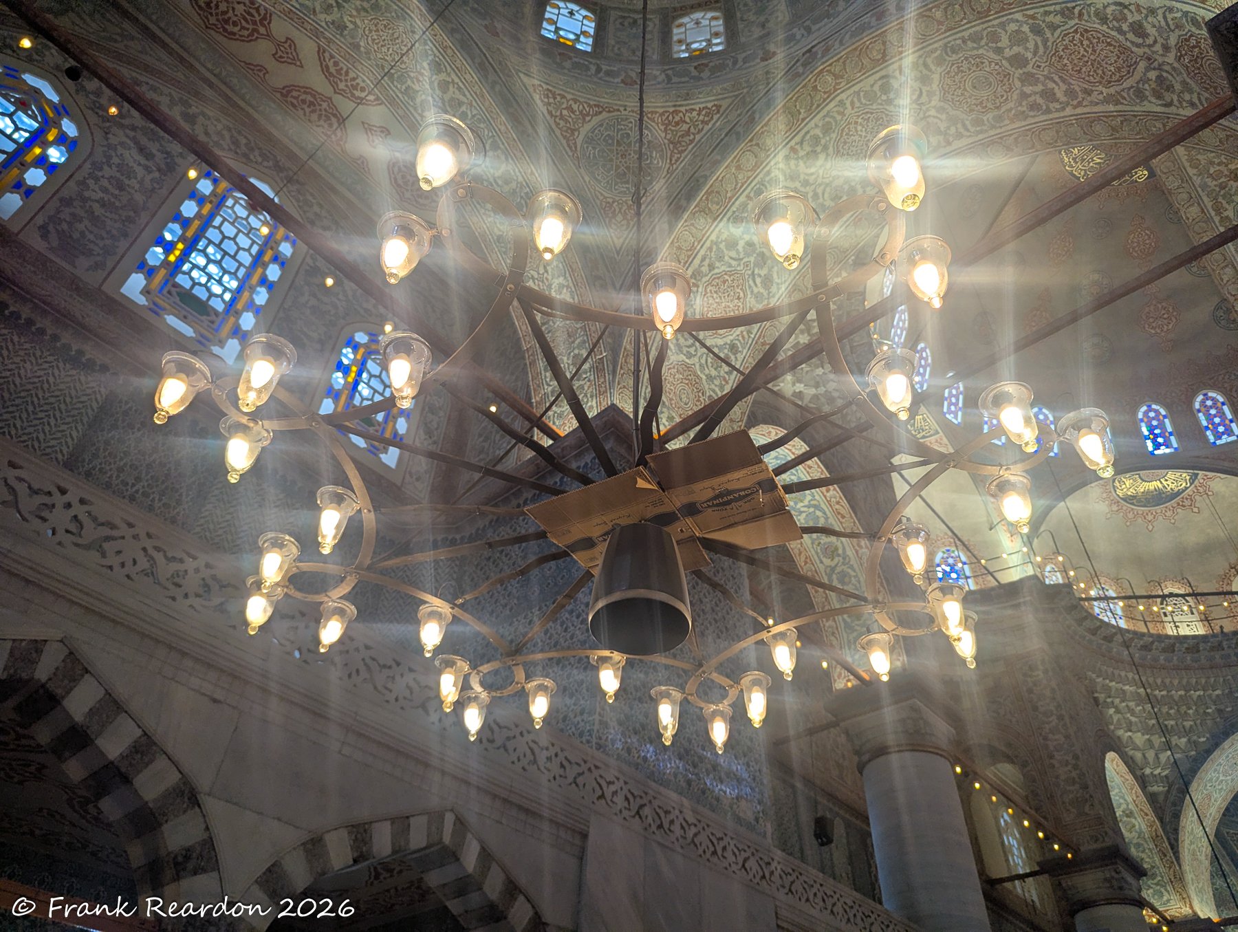 ooking up at a massive, ornate hanging chandelier casting a warm glow beneath the intricately painted interior dome.