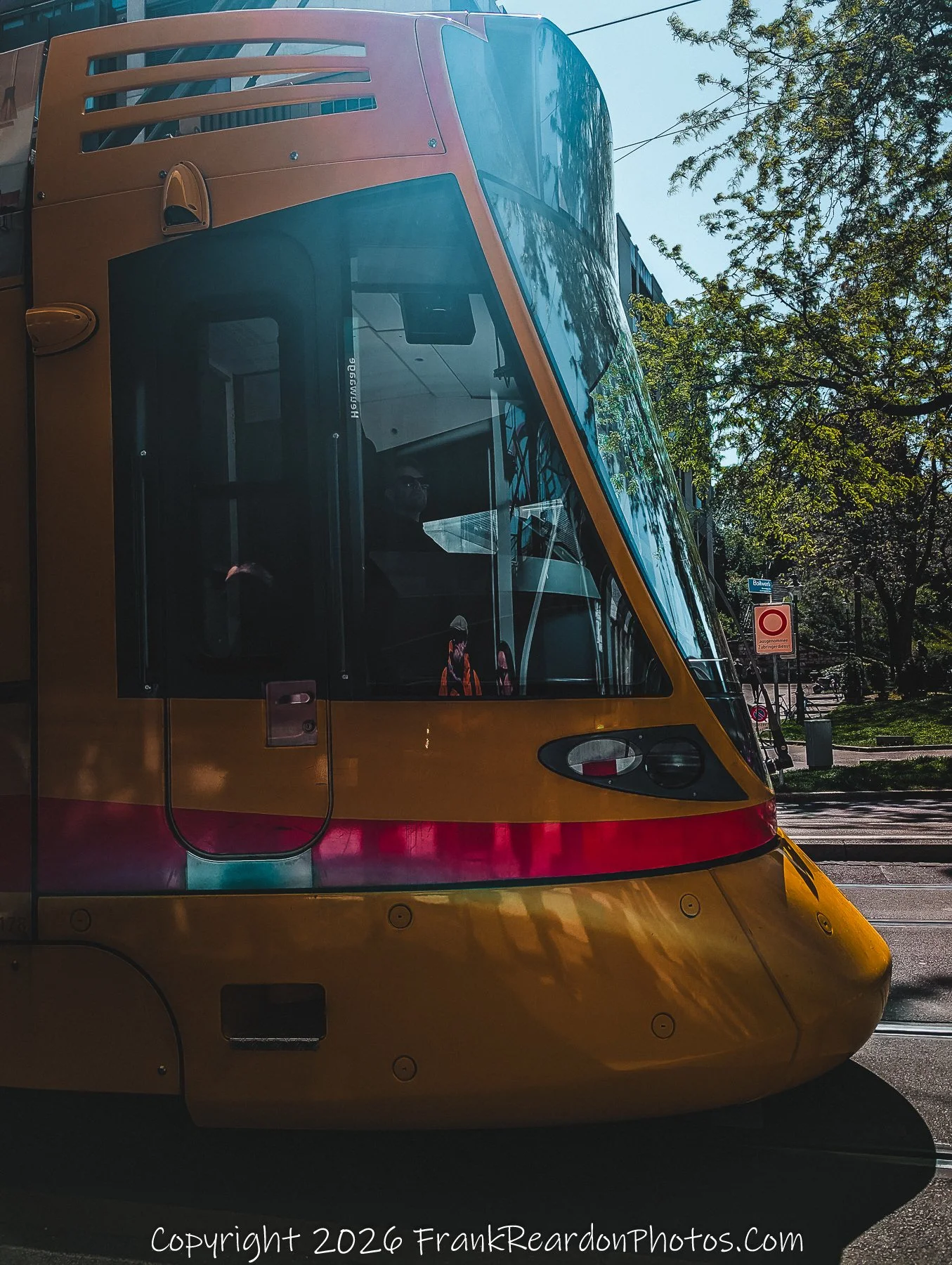 "Transit Connection" A close-up, side-profile shot of a yellow-and-red tram in the clear morning light.