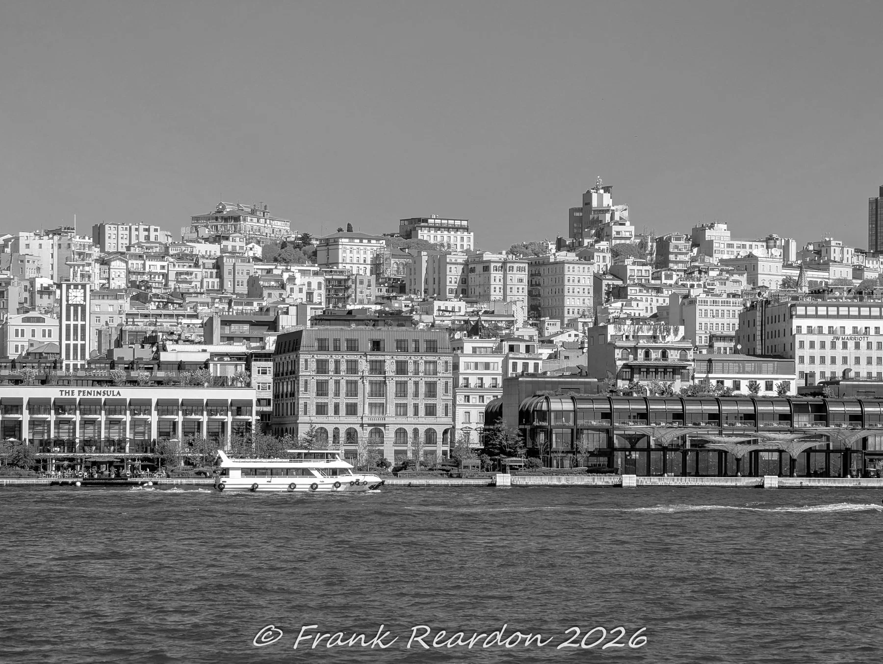 A black-and-white architectural view of the Karaköy shoreline, showcasing luxury hotels like The Peninsula Istanbul, historic stone buildings, and modern waterfront developments along the Bosphorus.