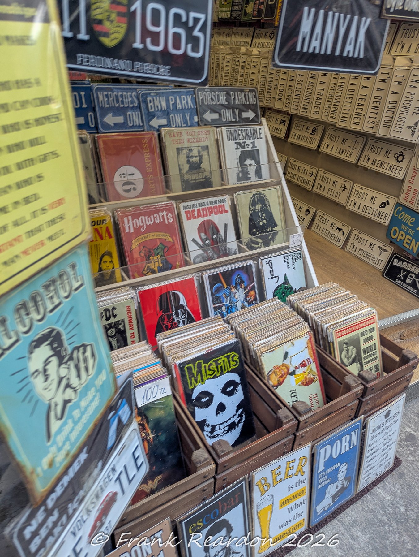 Shelves and bins filled with colorful pop culture tin signs, movie posters, and branded automotive memorabilia inside an Istanbul shop.