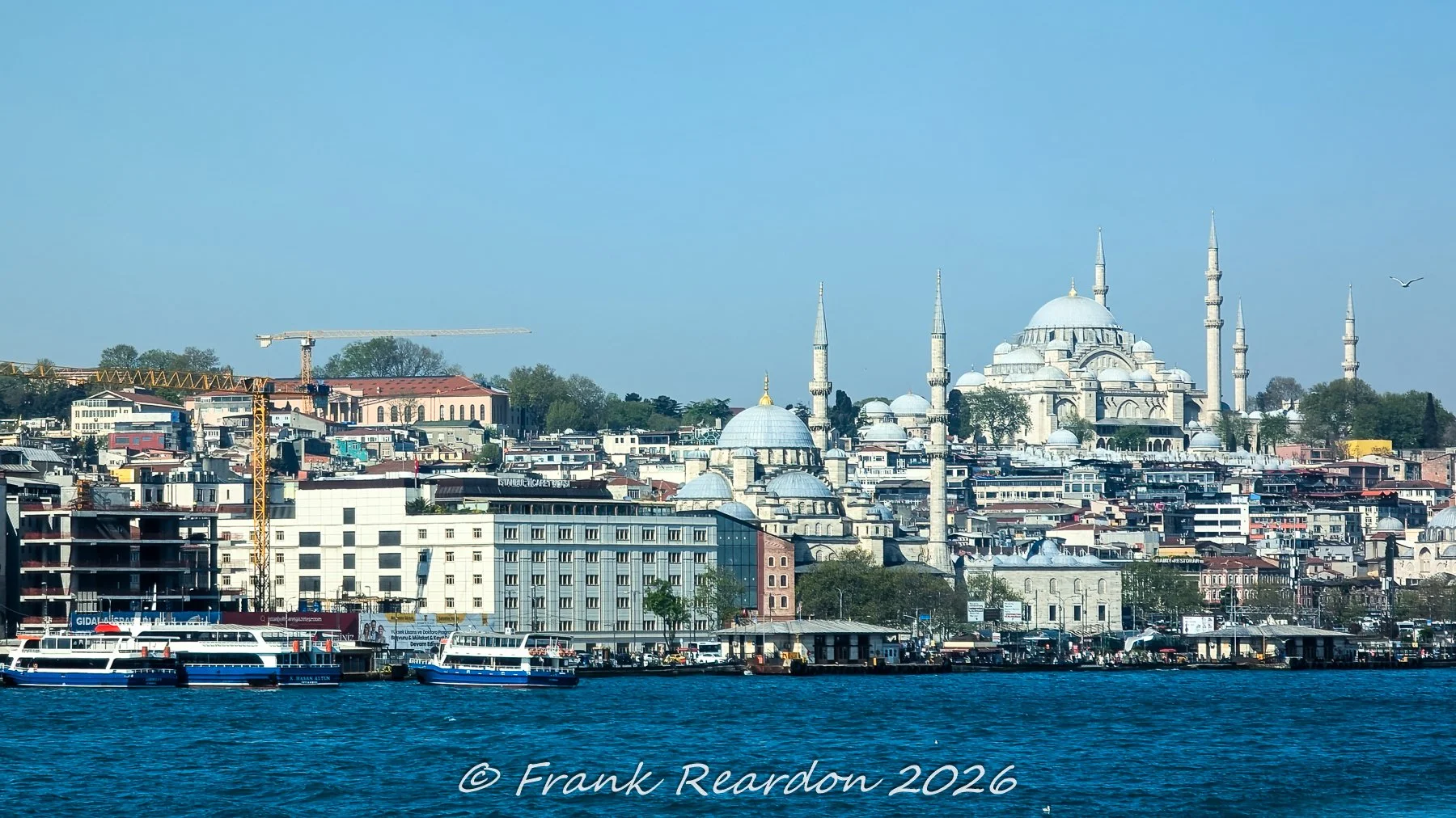 A daytime view across the water toward the historic Fatih district, highlighted by the magnificent silhouette of the 16th-century Süleymaniye Mosque and surrounding minarets.