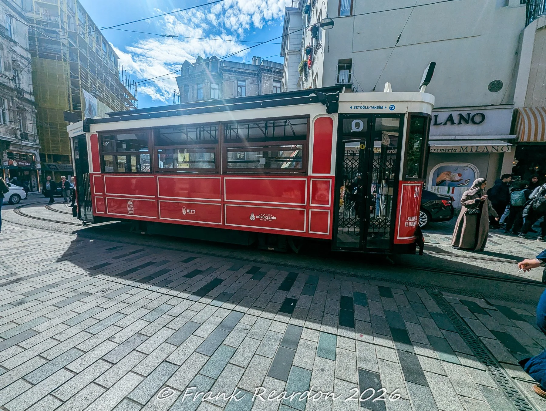 The iconic historic red nostalgic tram traveling along the paved tracks of Istiklal Avenue in the Beyoğlu district.