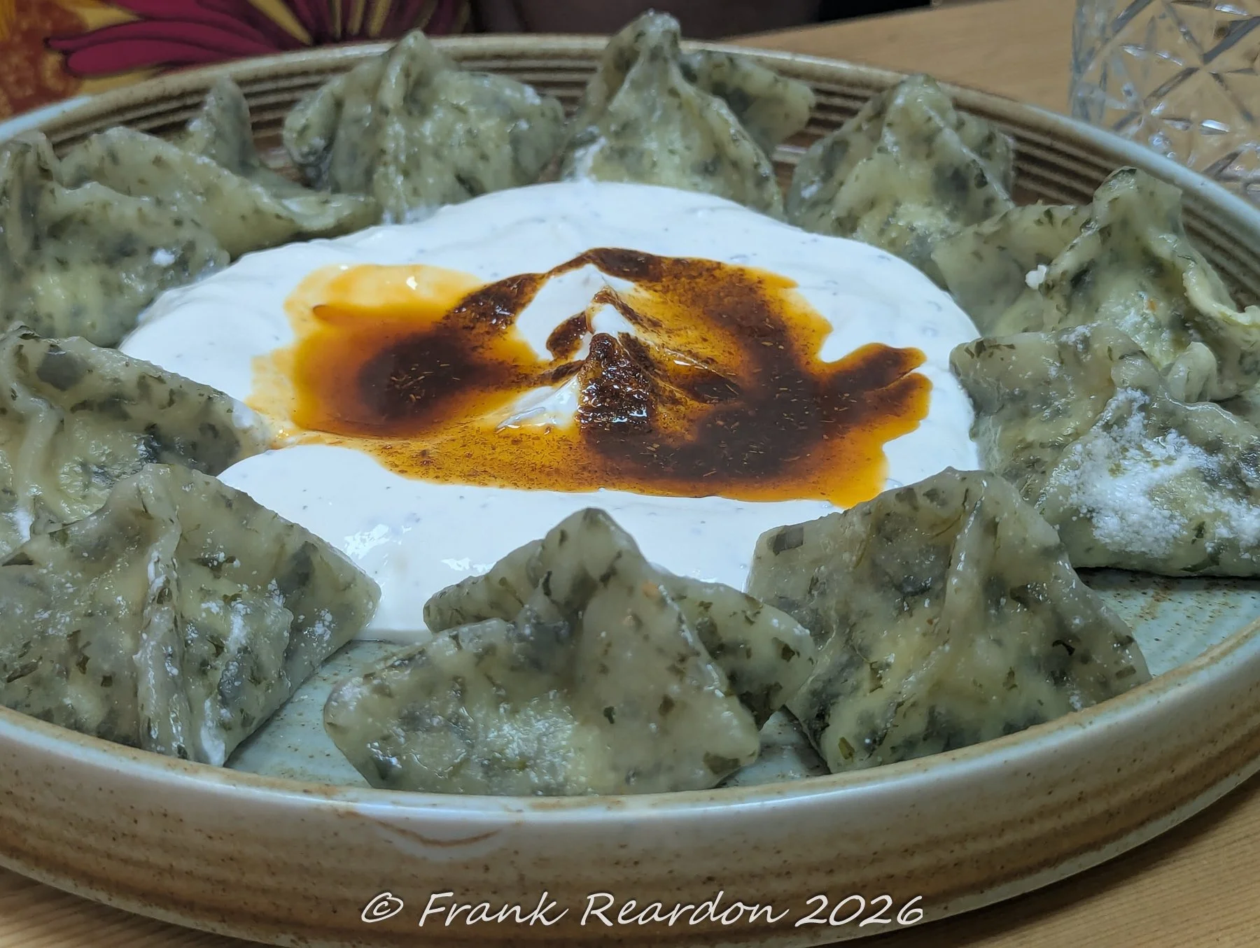 A plate of traditional Turkish Gluten Free dumplings (mantı) served with garlic yogurt and a drizzle of spiced red pepper butter.