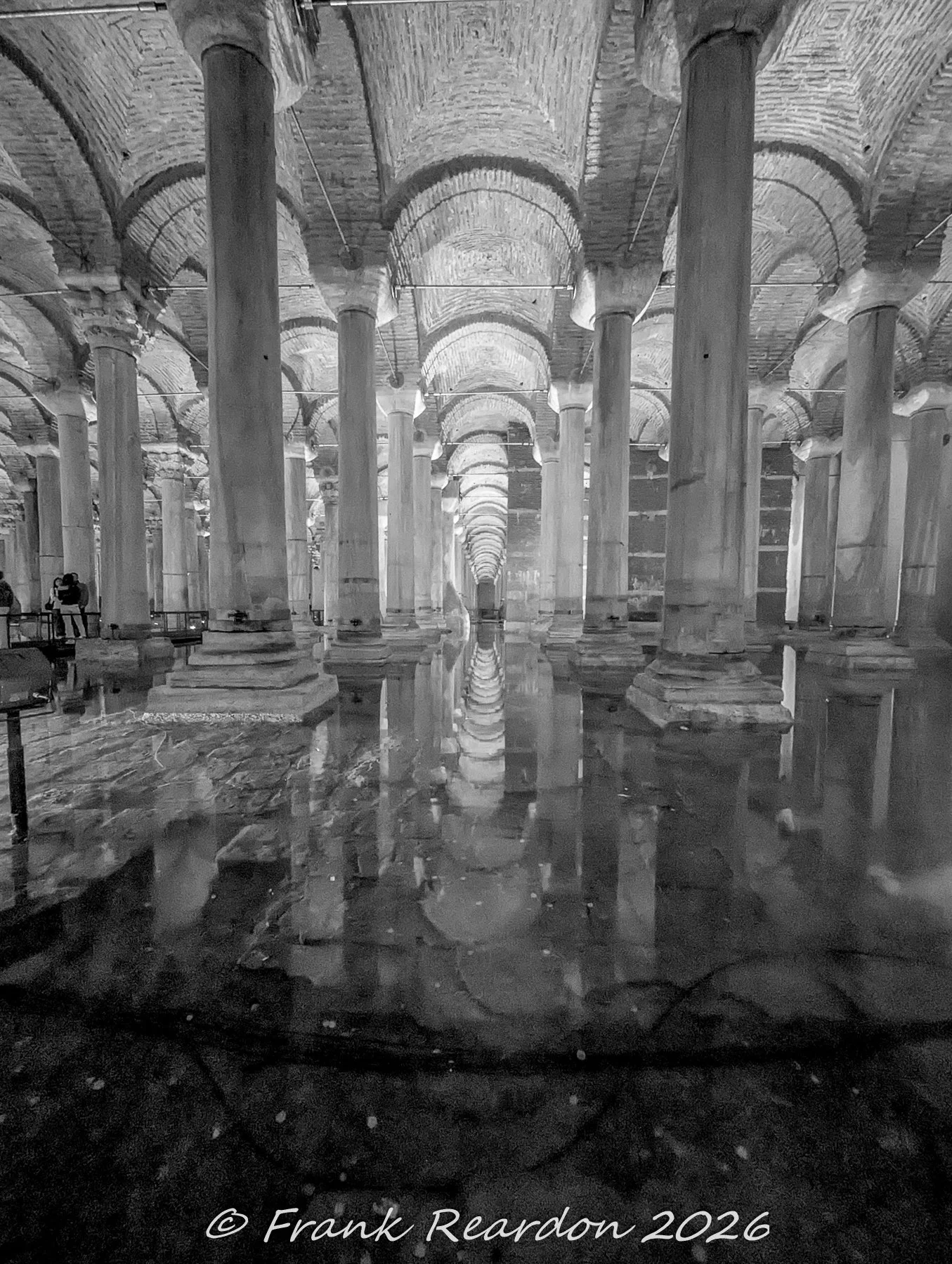 A moody black-and-white long exposure capturing the endless repetition of marble columns and their shimmering reflections in the underground reservoir.
