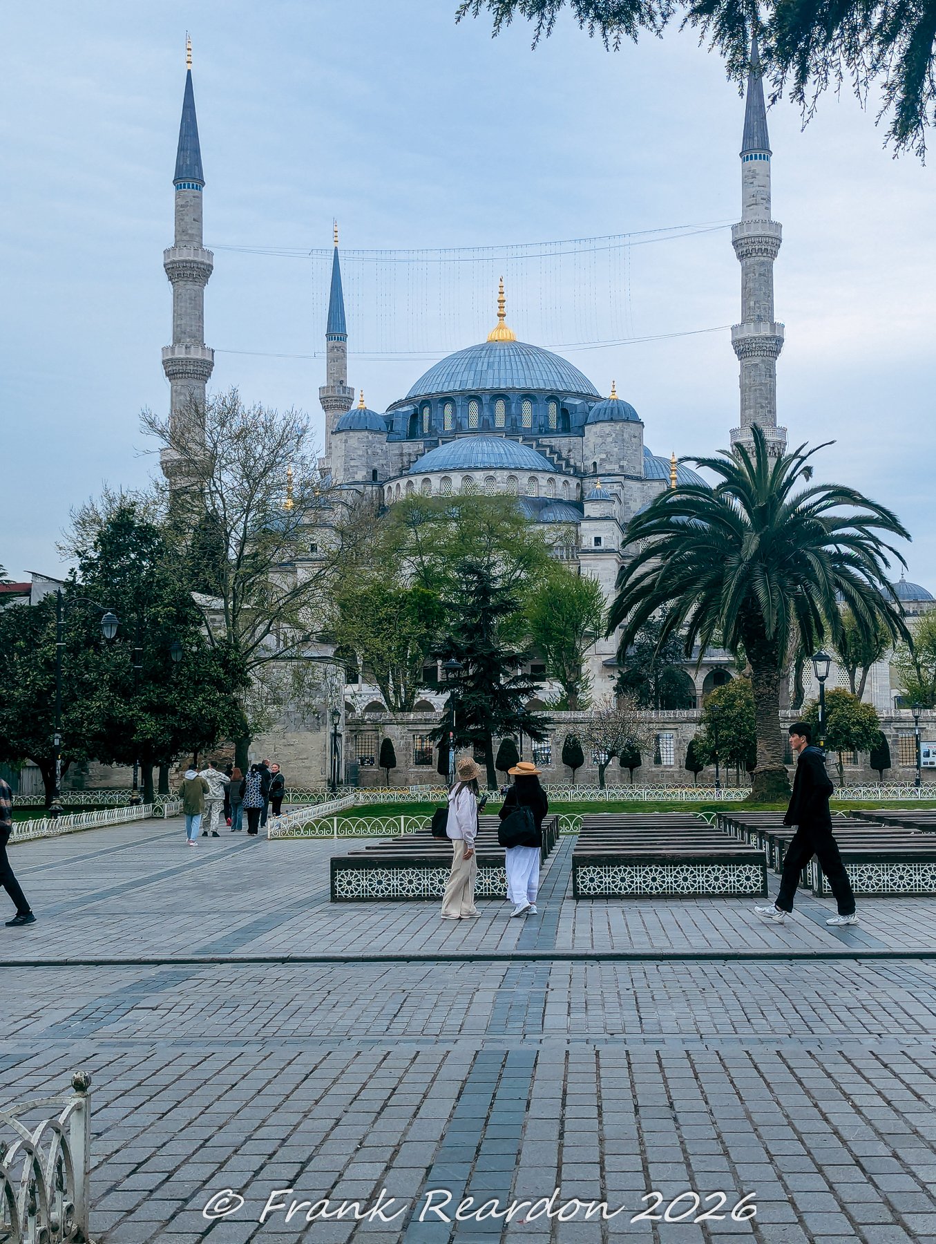 Visitors strolling through the exterior courtyard and gardens surrounding the magnificent Sultan Ahmed Mosque (Blue Mosque) in Istanbul.