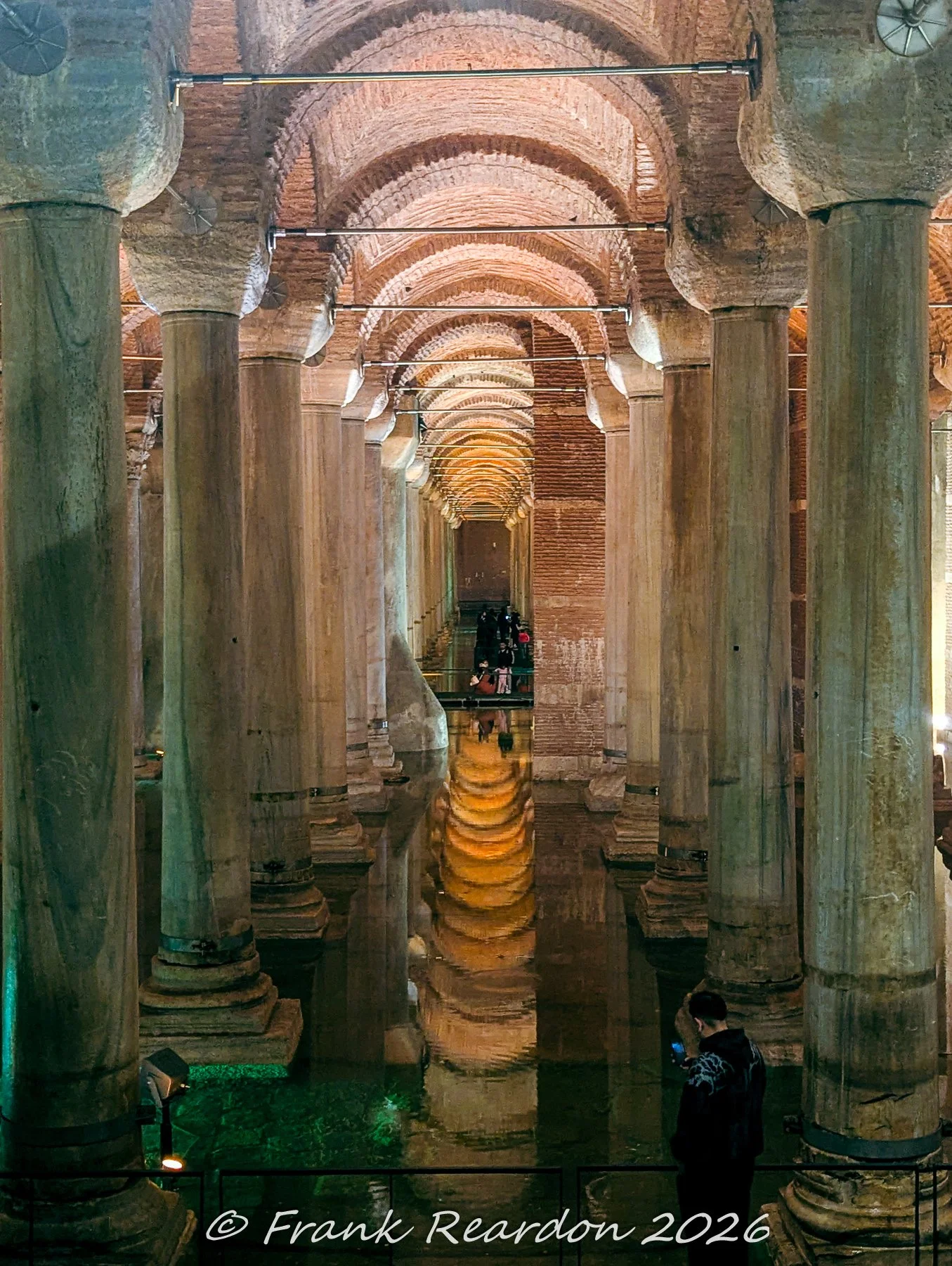 A striking perspective of marble columns and glowing vaulted ceilings perfectly reflected on the calm water surface of the Basilica Cistern.