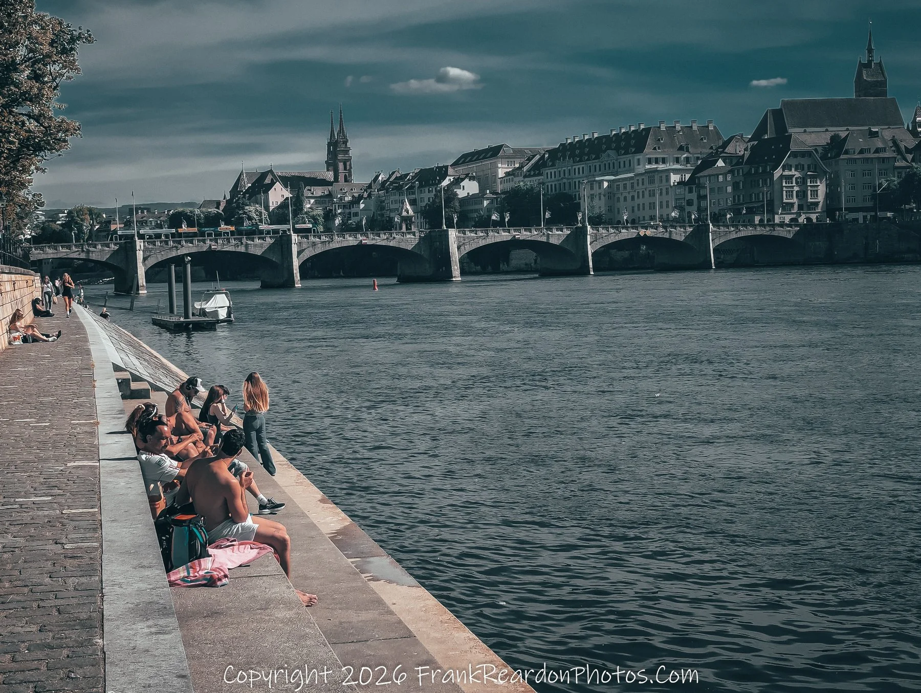 “Afternoon by the Rhine” Sunbathers and dreamers gather along the stone edge, framed by bridges and cathedral spires.