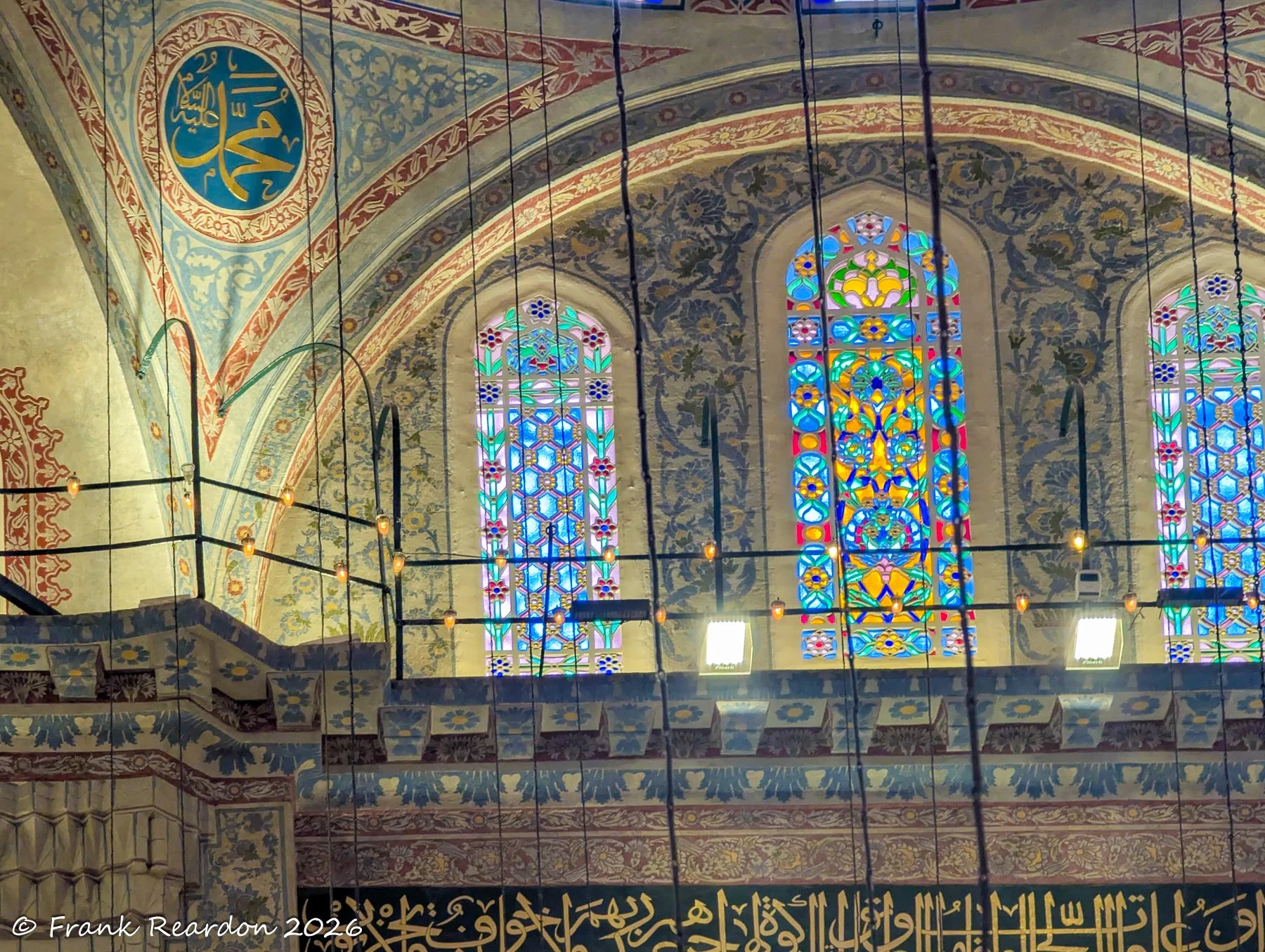 Richly colored stained-glass windows filtering daylight through detailed floral and geometric wall murals.