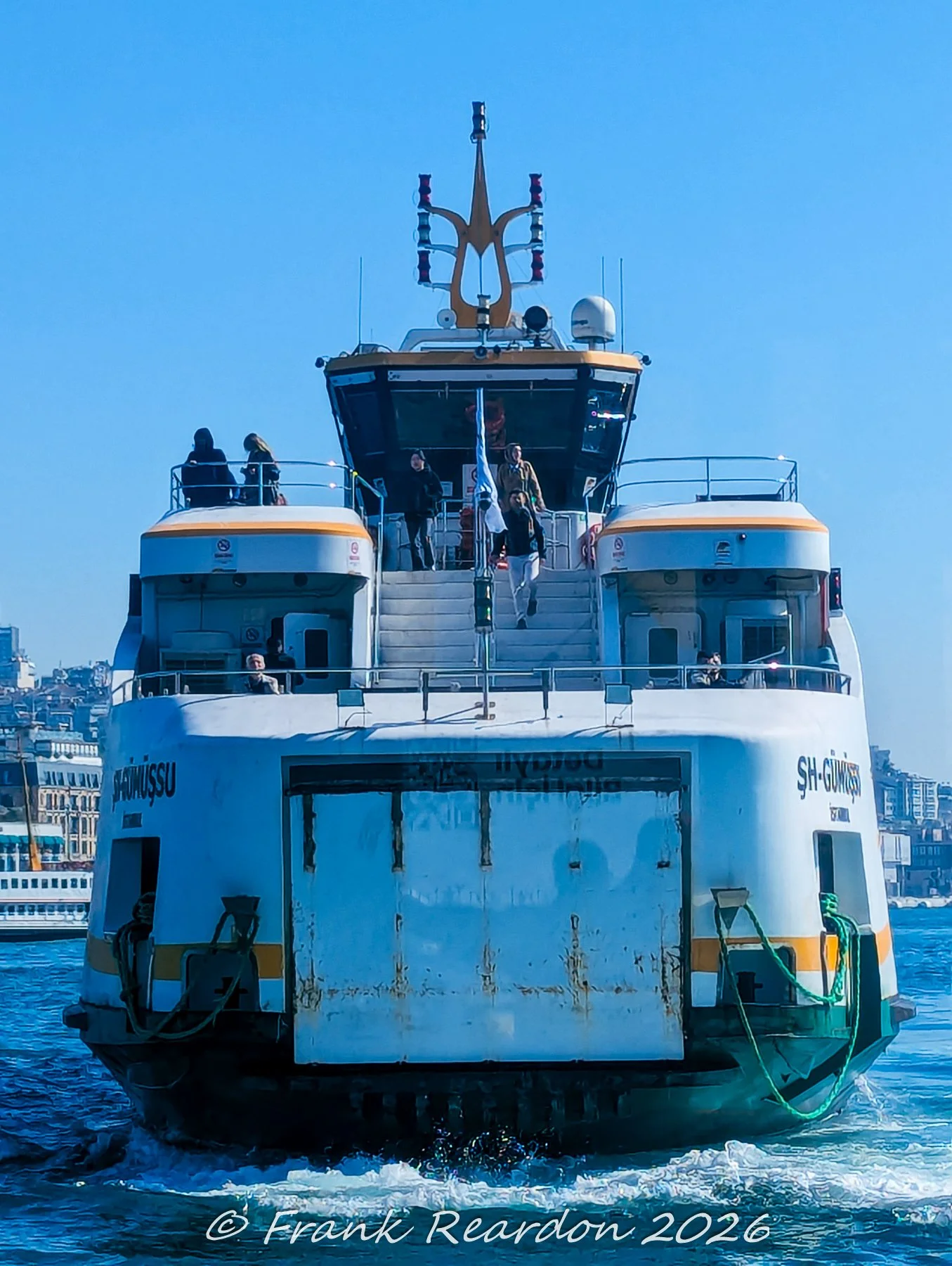 The bow view of the municipal passenger ferry ŞH-Gümüşsu cutting through the choppy waters of the Bosphorus with passengers on the upper decks.