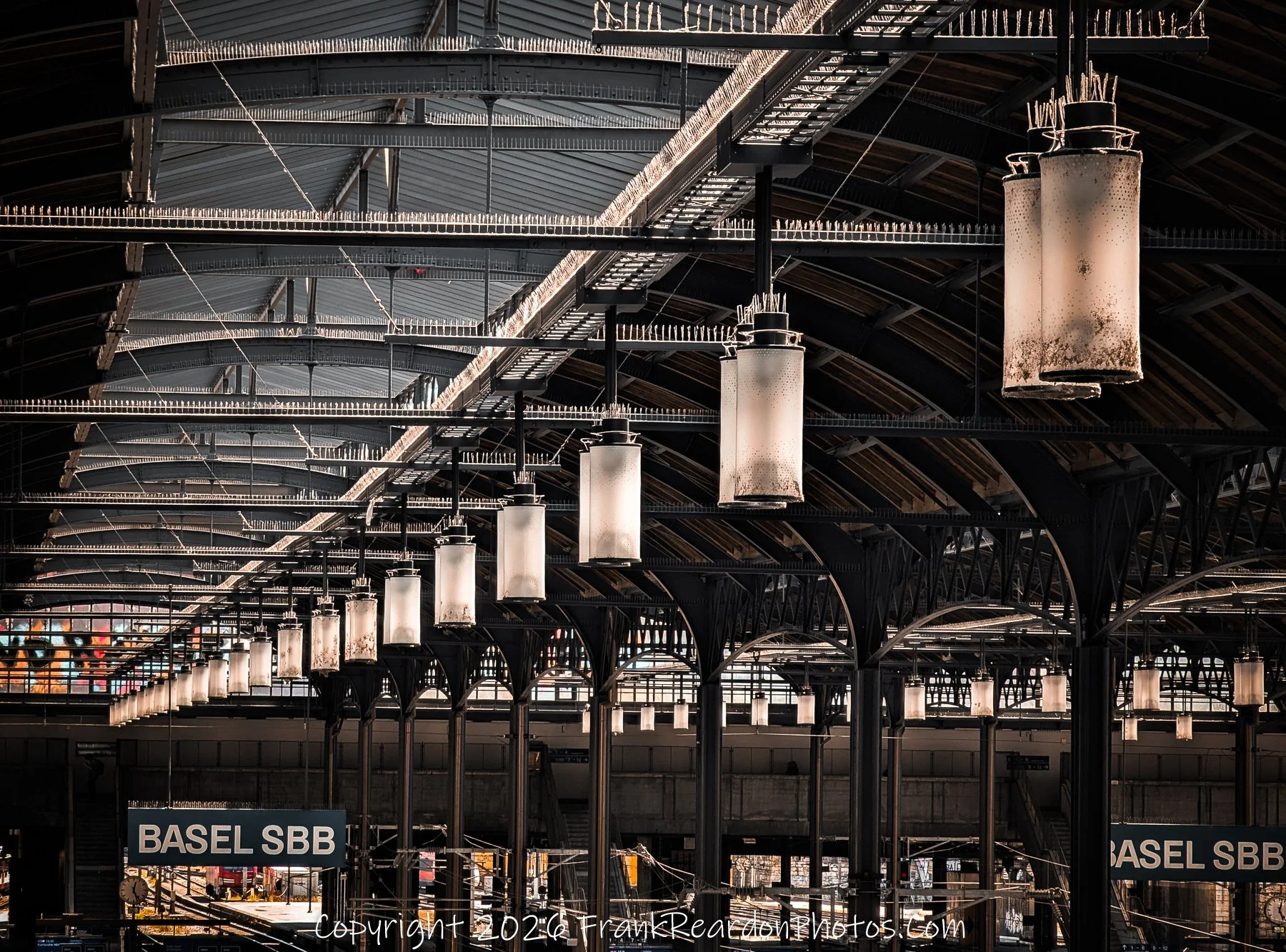 "Architectural Symmetry" A focused look at the ceiling structure and the hanging lights of the station, emphasizing the geometric patterns and industrial design.